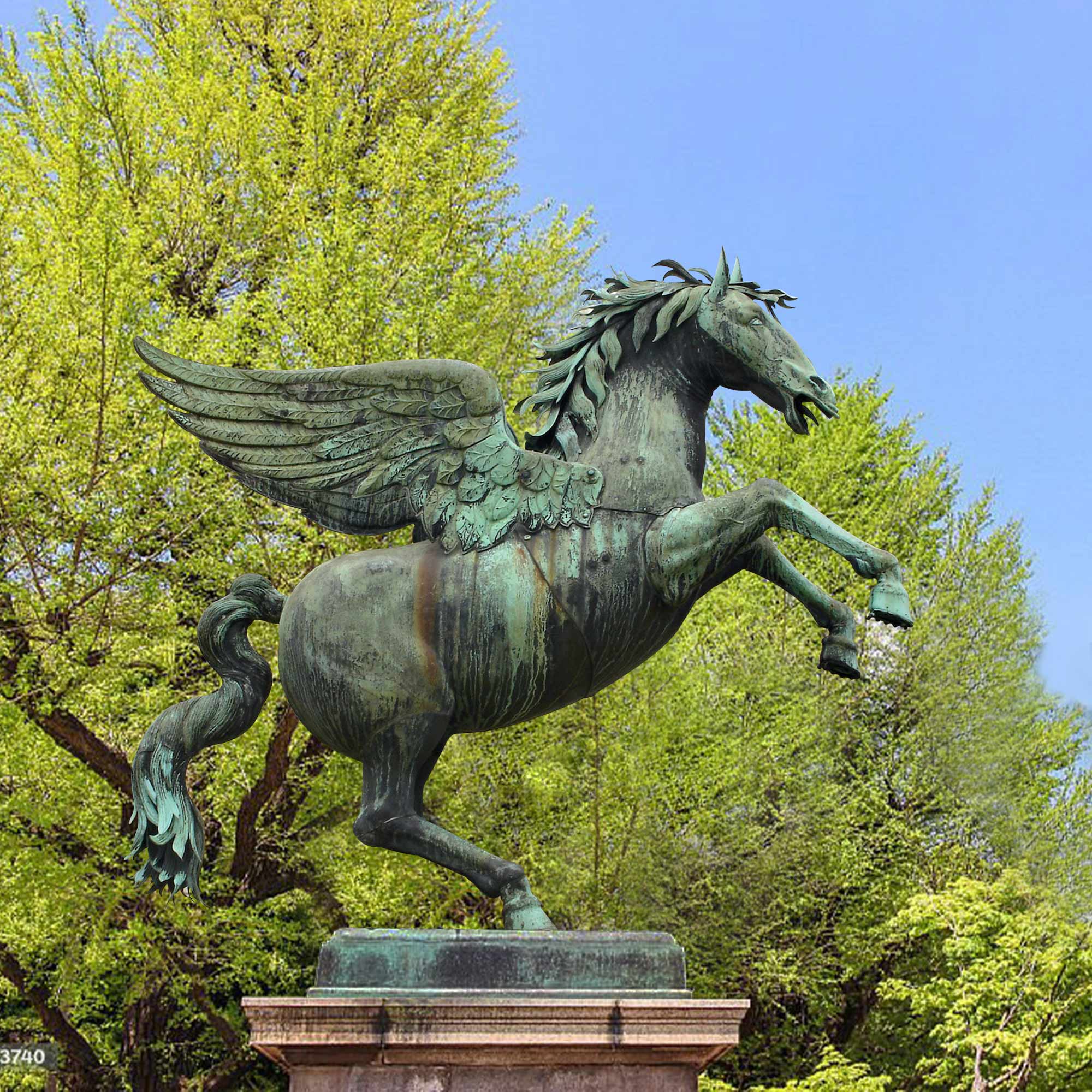 A bronze statue of a rearing Pegasus with detailed wings, set outdoors against a backdrop of green trees and a blue sky.