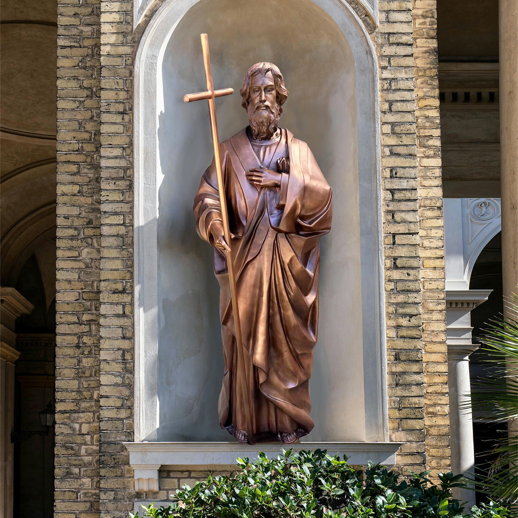 life-size bronze religious statue of St. Philip with cross, symbolizing faith and devotion in antique bronze finish, setting outside garden.
