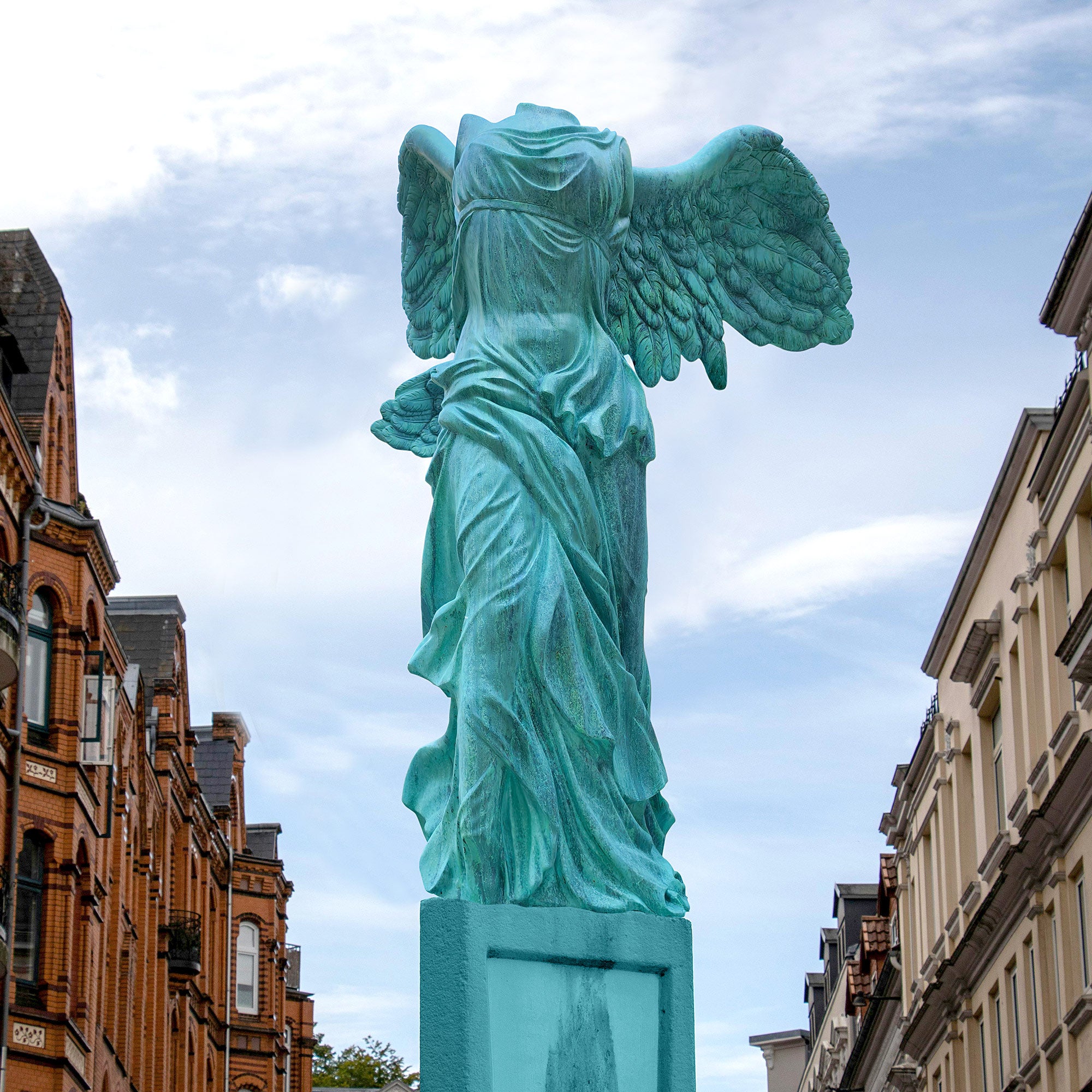 Bronze Winged Nike Victory of Samothrace sculpture with patina green finish, showcasing classical drapery and outstretched wings display in a street