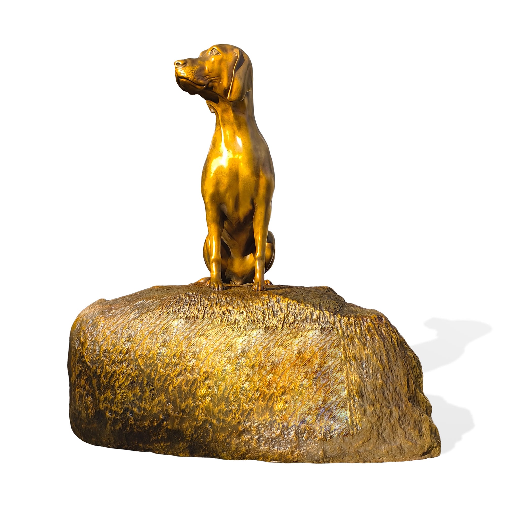 Gold dog statue on a rocky base against a white background