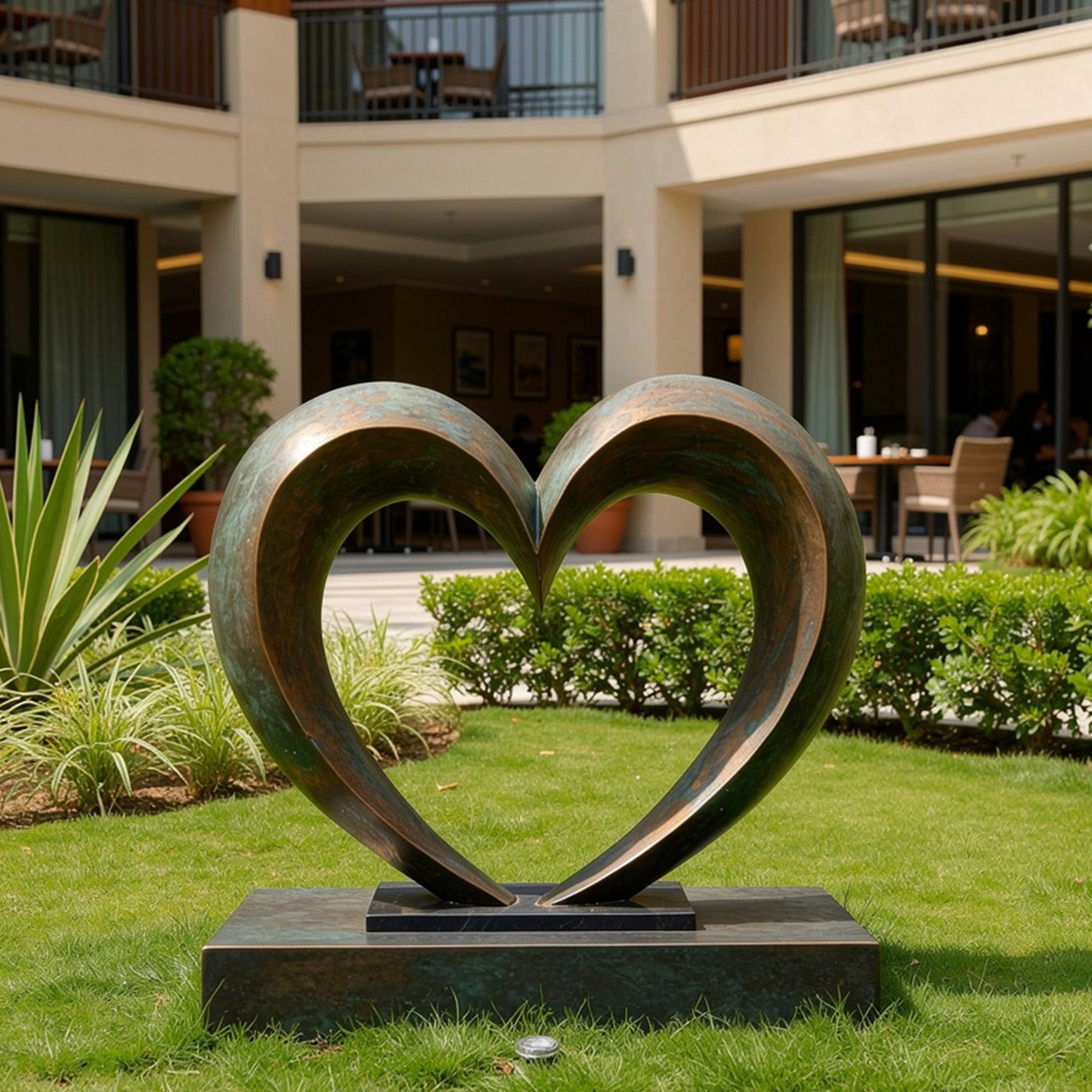 Bronze heart sculpture in a garden setting with a building in the background