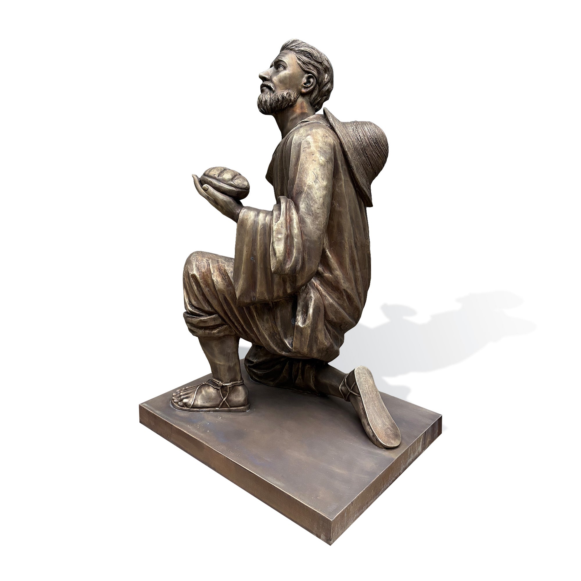 Side view of a bronze Saint Juan Diego statue showcasing realistic drapery, handcrafted details, and a humble kneeling posture inspired by Christian faith.