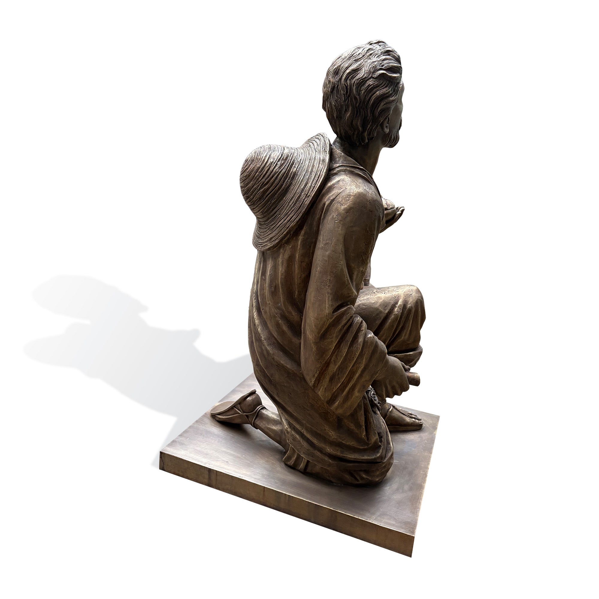 Rear view of a bronze Saint Juan Diego sculpture featuring flowing garments, a traditional hat, and finely crafted bronze detailing.