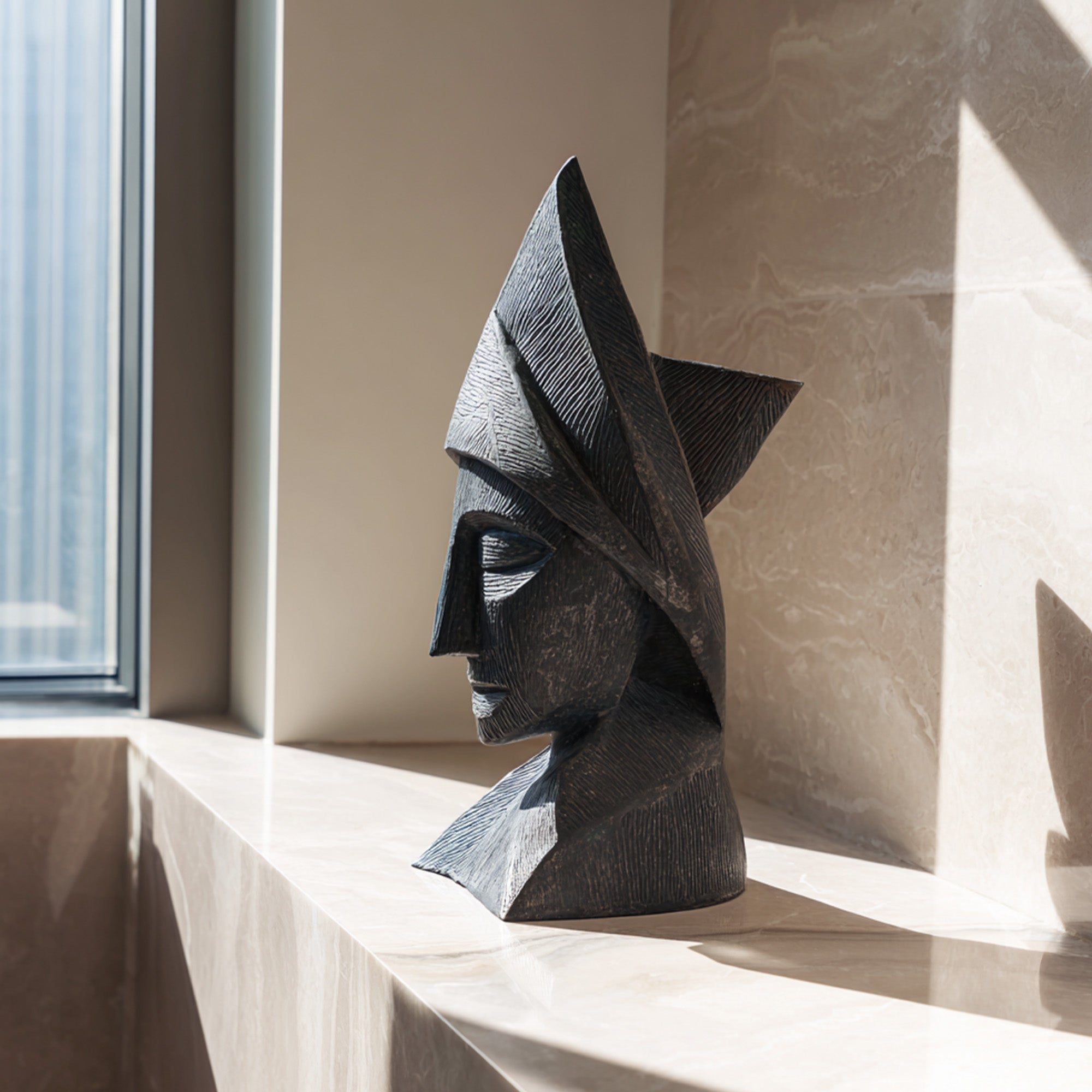 Cubist style bronze head sculpture displayed on a marble windowsill, featuring geometric portrait form, dark antique finish, and modern interior art decor