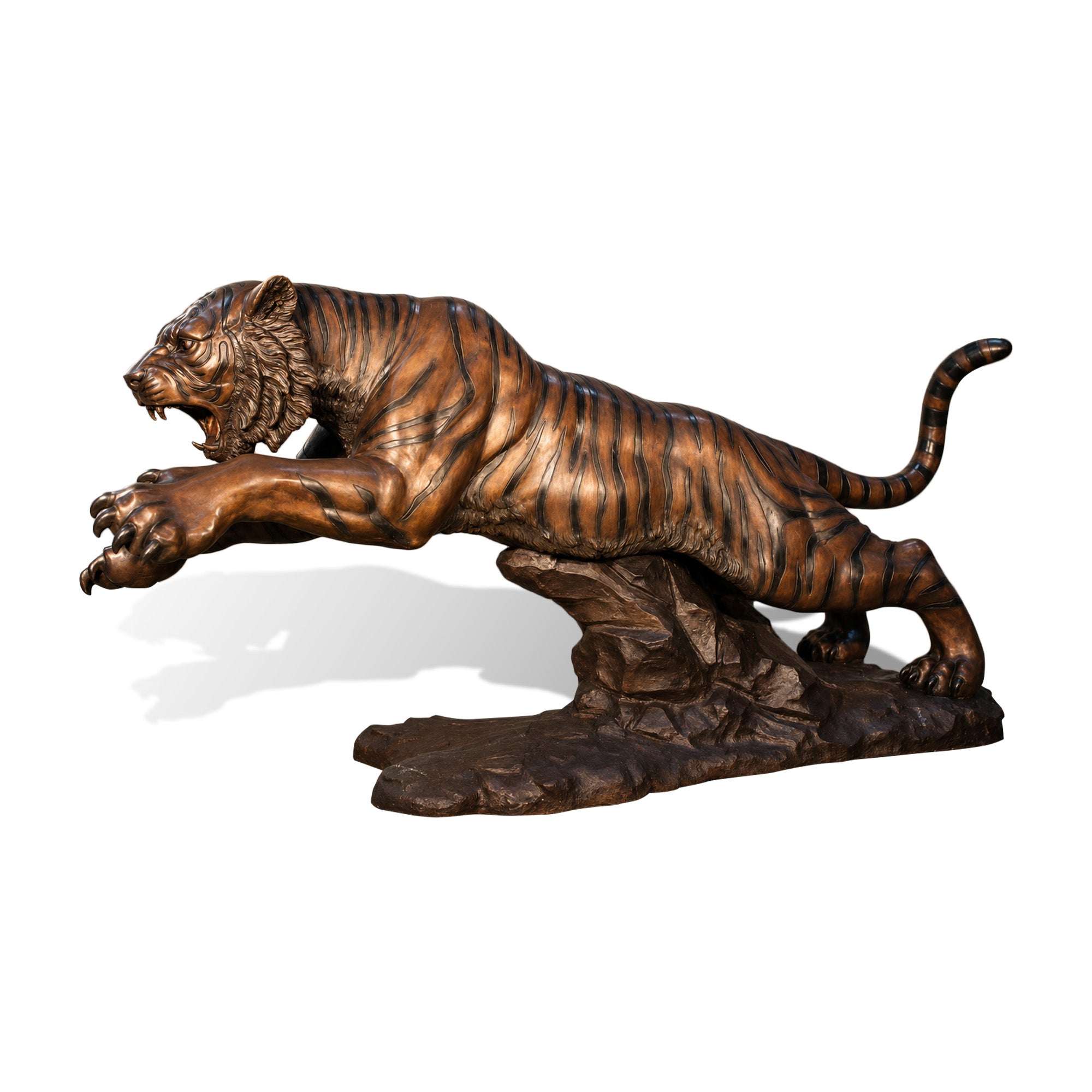 Bronze tiger sculpture in dynamic stalking pose with extended limbs, displayed outdoors on a rocky base.