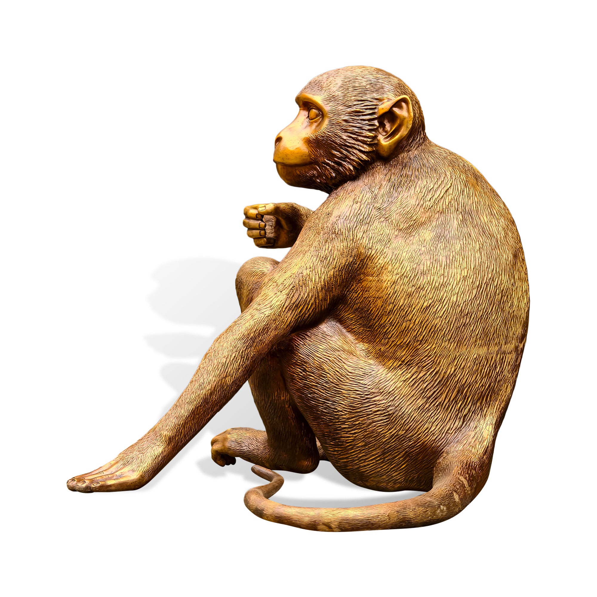 Side profile view of a golden bronze monkey sculpture with Chinese zodiac symbolism, seated body, extended arm, bent legs, curled tail, and detailed fur texture on a white background.