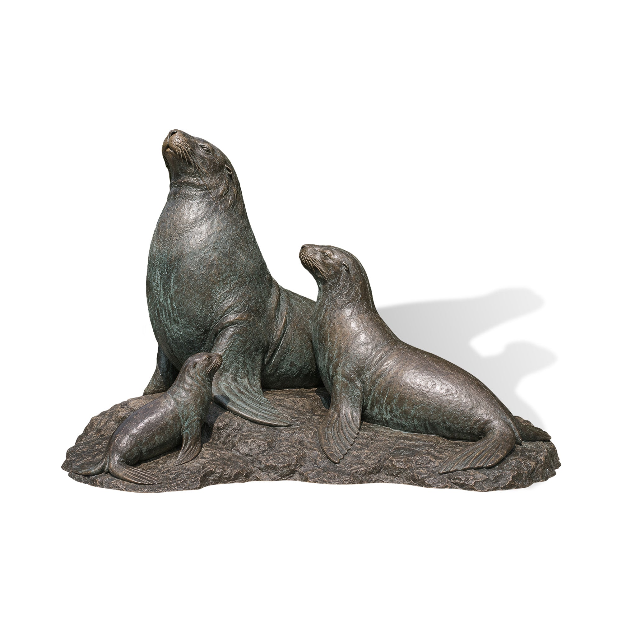 Realistic bronze seal family statue featuring adult and baby sea lions on a textured rock base near water.