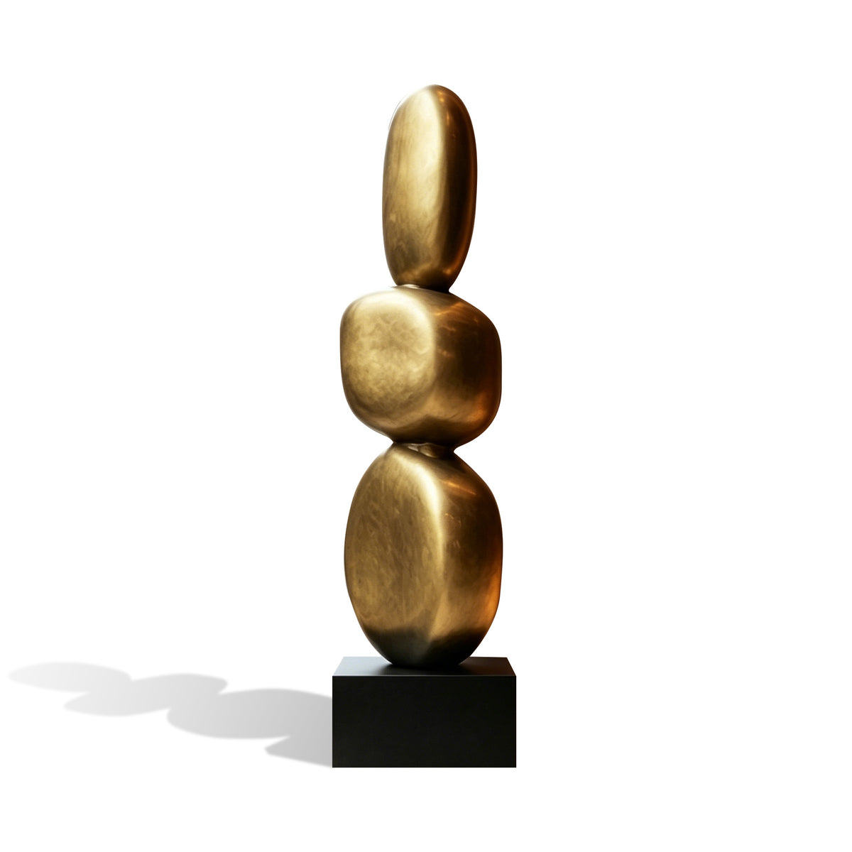 Abstract bronze stacked oval sculpture with three rounded forms, gold metallic finish, minimalist vertical design, and black pedestal base on white background