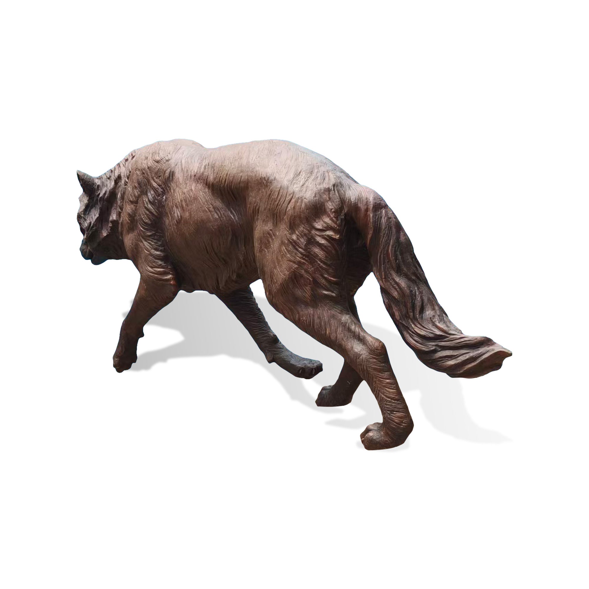 Profile view of a bronze wolf animal sculpture featuring a natural walking stance, textured fur details, expressive body shape, and handcrafted outdoor art design.