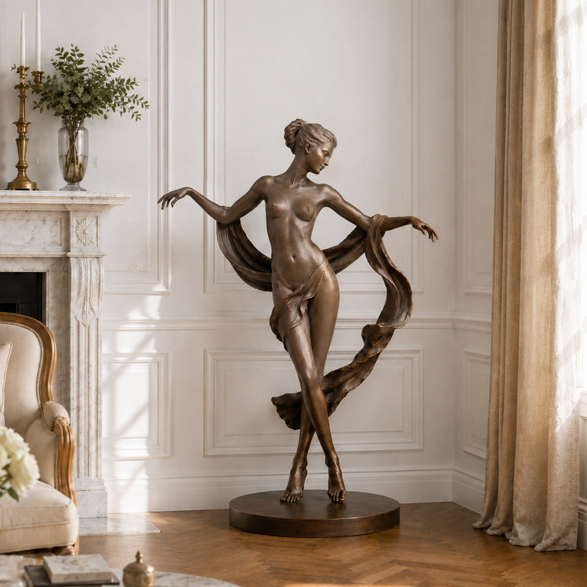 Bronze female dancer sculpture displayed in an elegant classical interior, featuring a poised woman with crossed legs, outstretched arms, and sweeping drapery, positioned on a round base beside a marble fireplace and tall curtains with a warm brown bronze finish.