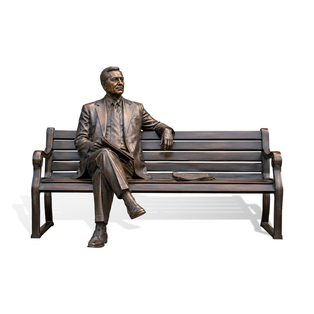 Life-size bronze seated man bench sculpture shown against a clean white background, featuring a formally dressed male figure in a suit and tie seated with crossed legs, one arm resting along the bench, a book or folder held on his lap, and finely modeled facial, clothing, and hand details.