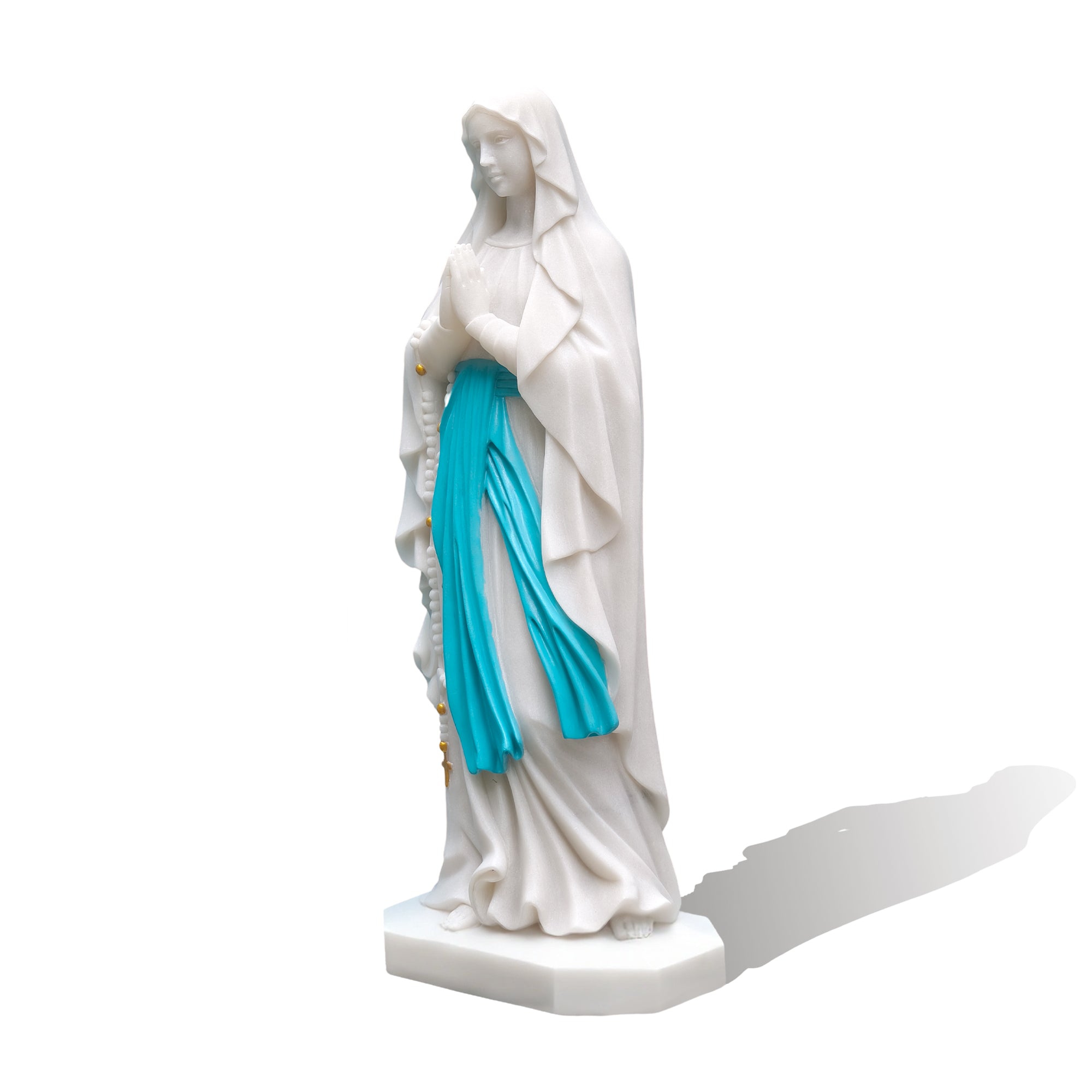 Side view of Our Lady of Lourdes marble statue showing carved drapery, white background
