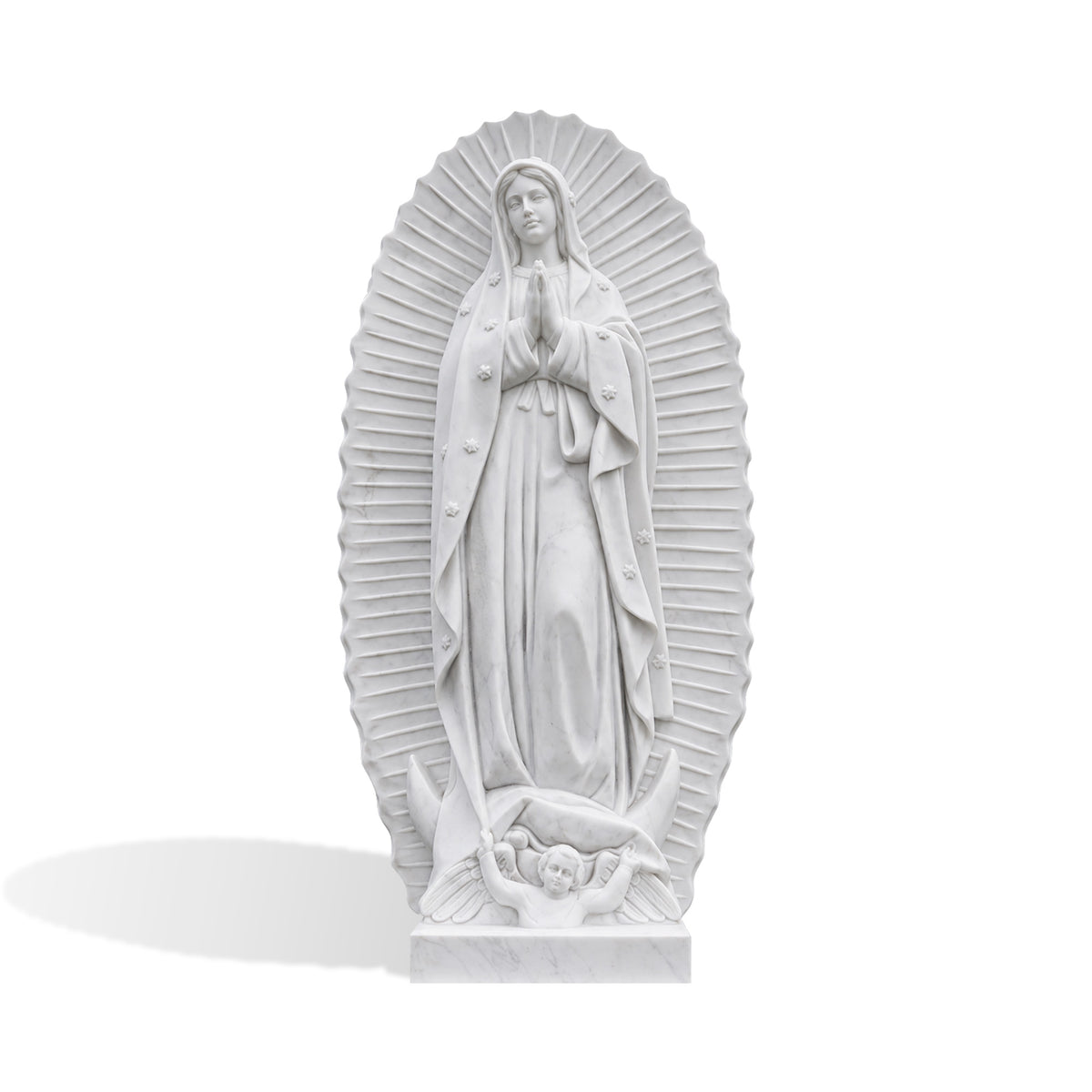 White marble Our Lady of Guadalupe statue featuring the Virgin Mary with hands joined in prayer, a star-decorated flowing mantle, radiant sunburst backdrop, crescent moon, and carved angel figure at the base.