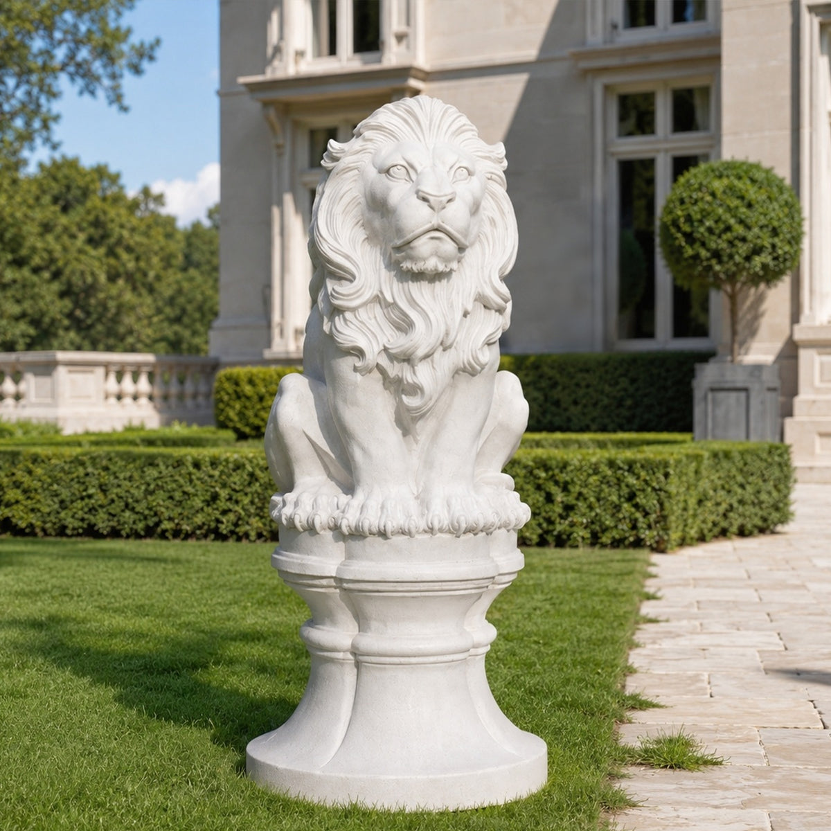 Seated white marble lion sculpture with a sculpted wavy mane and layered pedestal beside a stone pathway in a formal estate garden