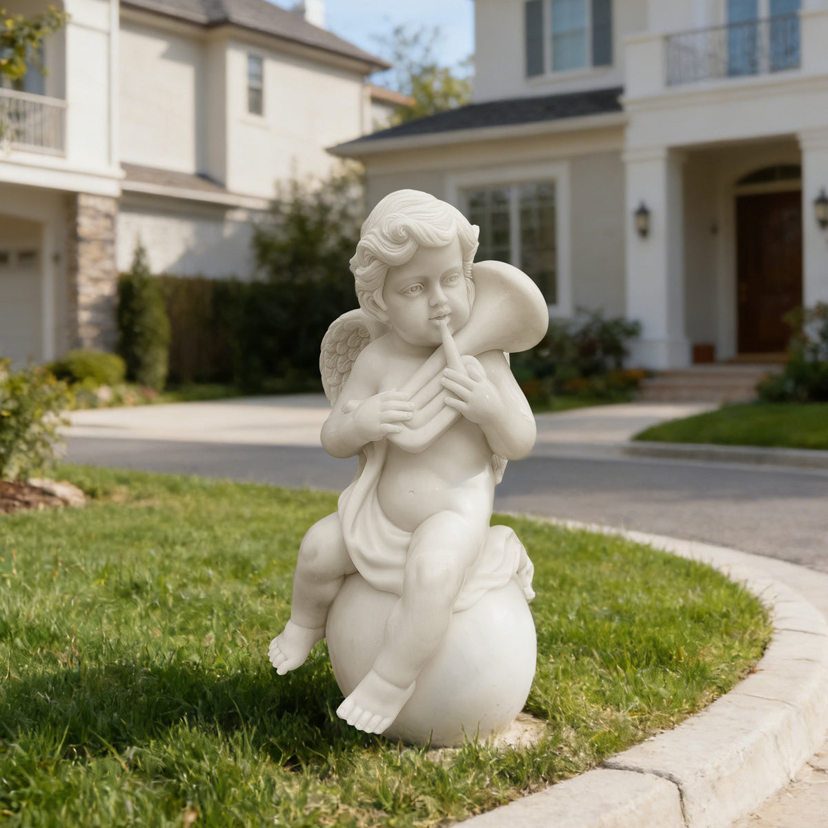 White marble cherub garden statue playing a curved horn while seated on a sphere, displayed on a green lawn outside a luxury villa.