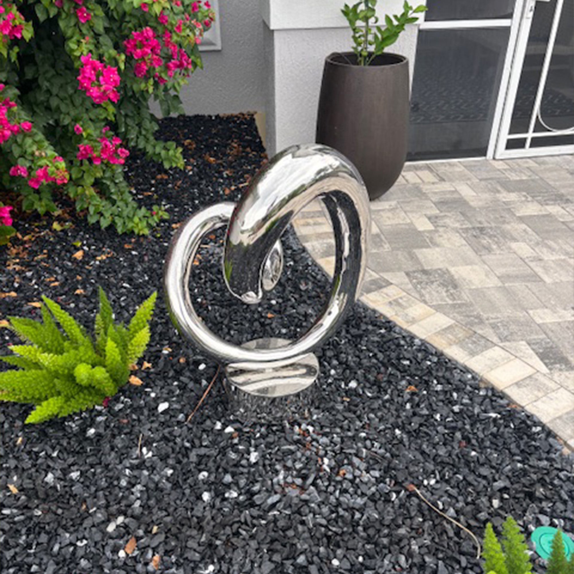 polished stainless steel heart shaped loop sculpture in garden decor