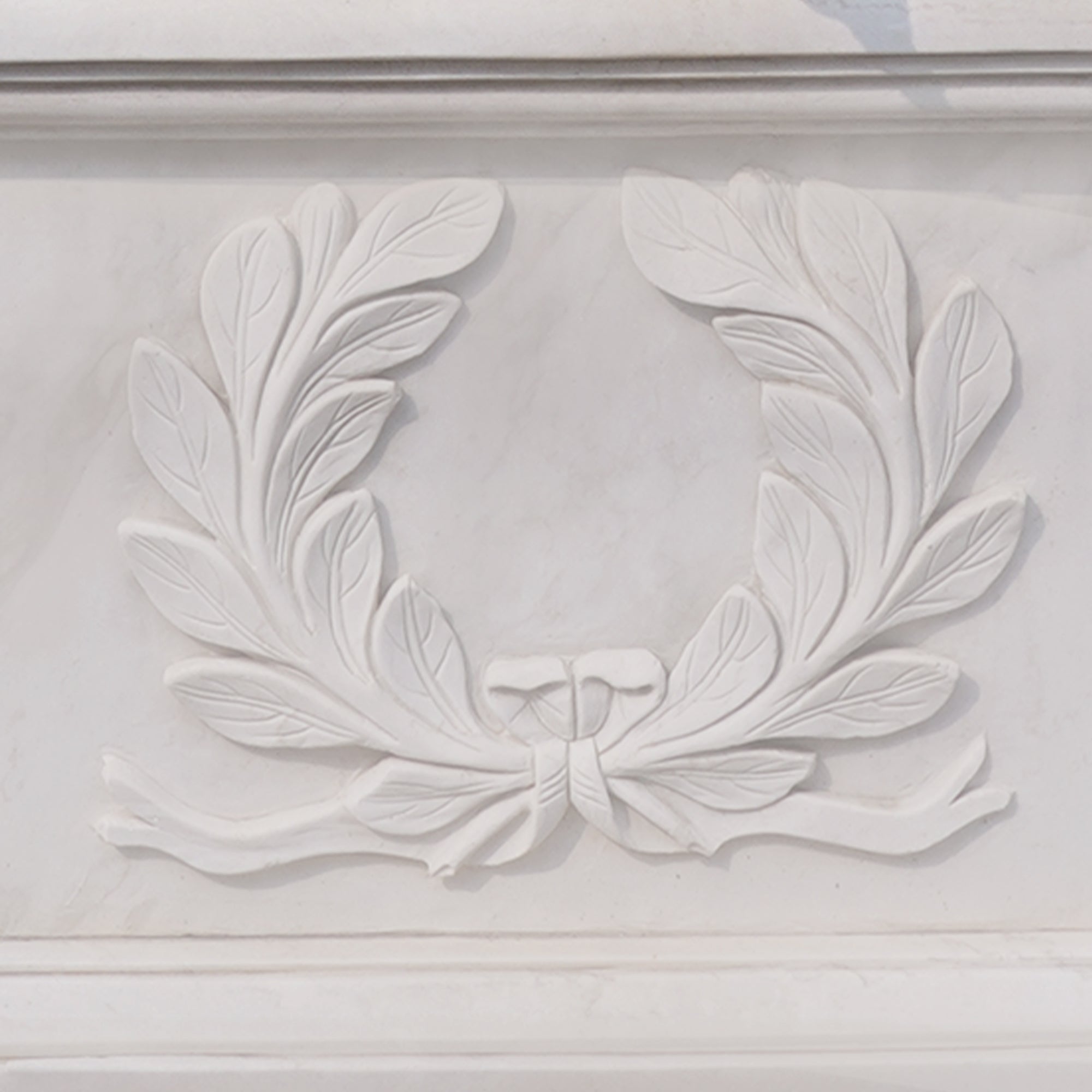 hand-carved white marble pedestal featuring a classical laurel wreath motif symbolizing honor and education in a neoclassical mother and children sculpture