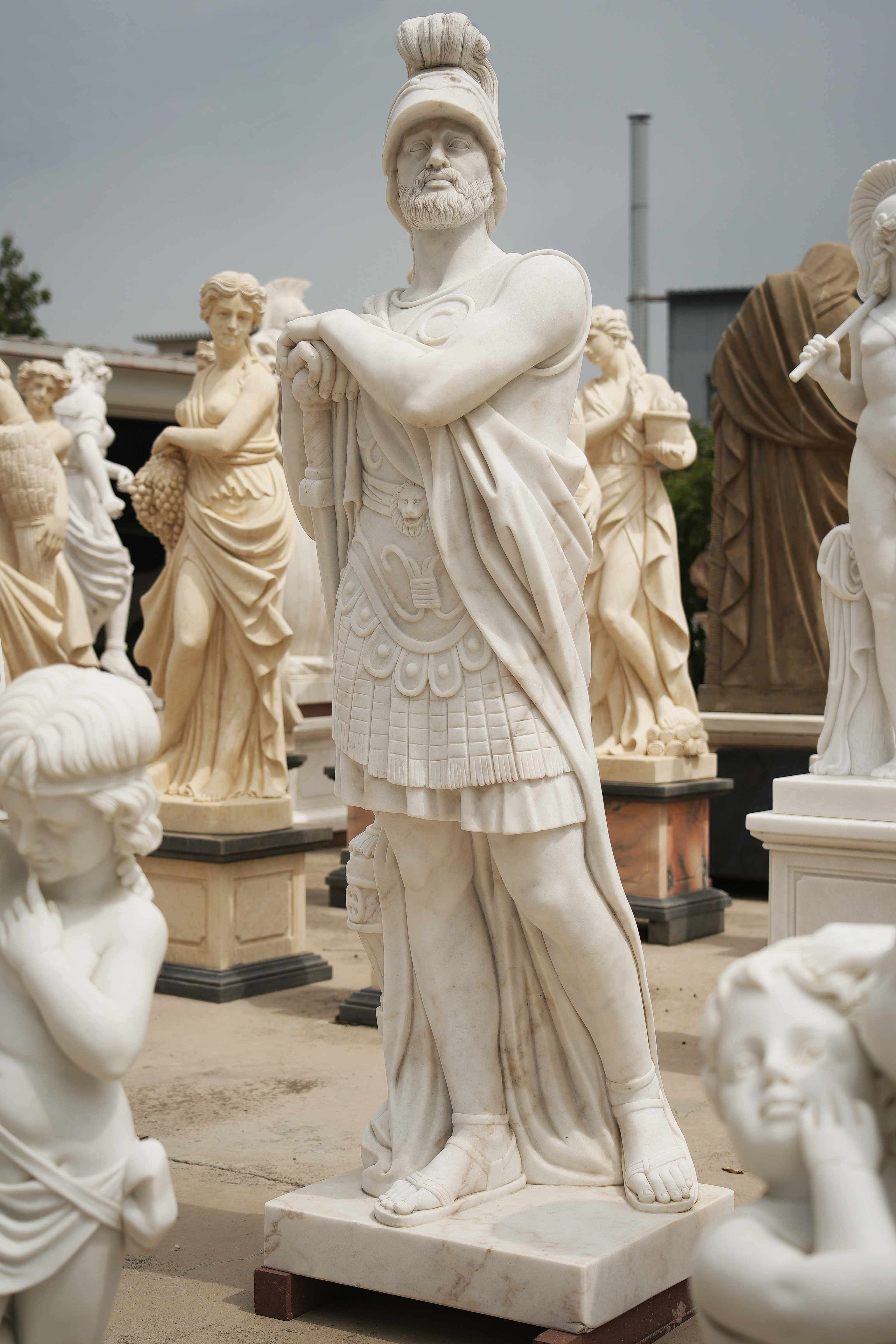 Marble statue of a Roman warrior with detailed armor, standing confidently among other classical sculptures in an outdoor setting
