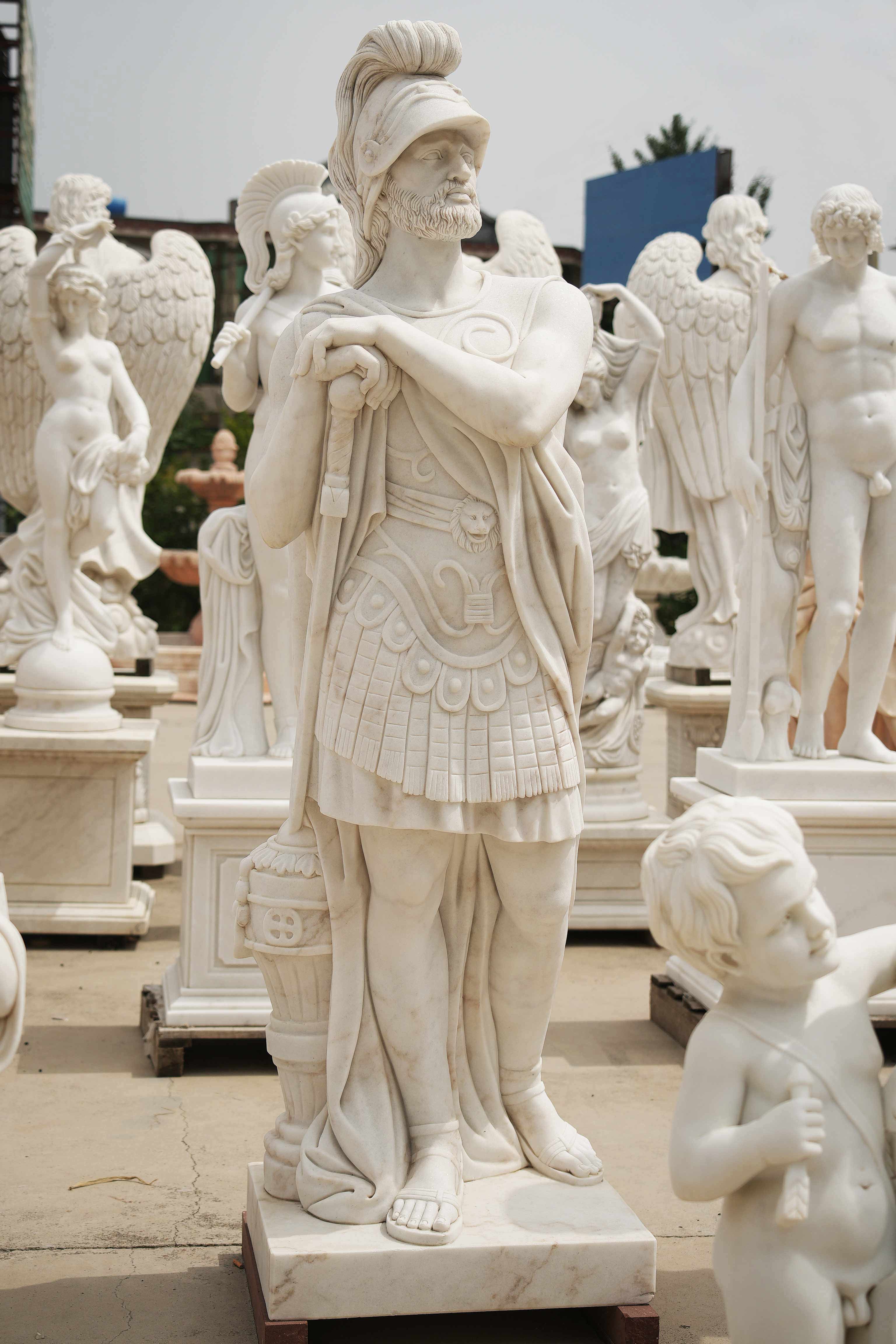 Marble statue of a Roman warrior with detailed armor, standing confidently among other classical sculptures in an outdoor setting