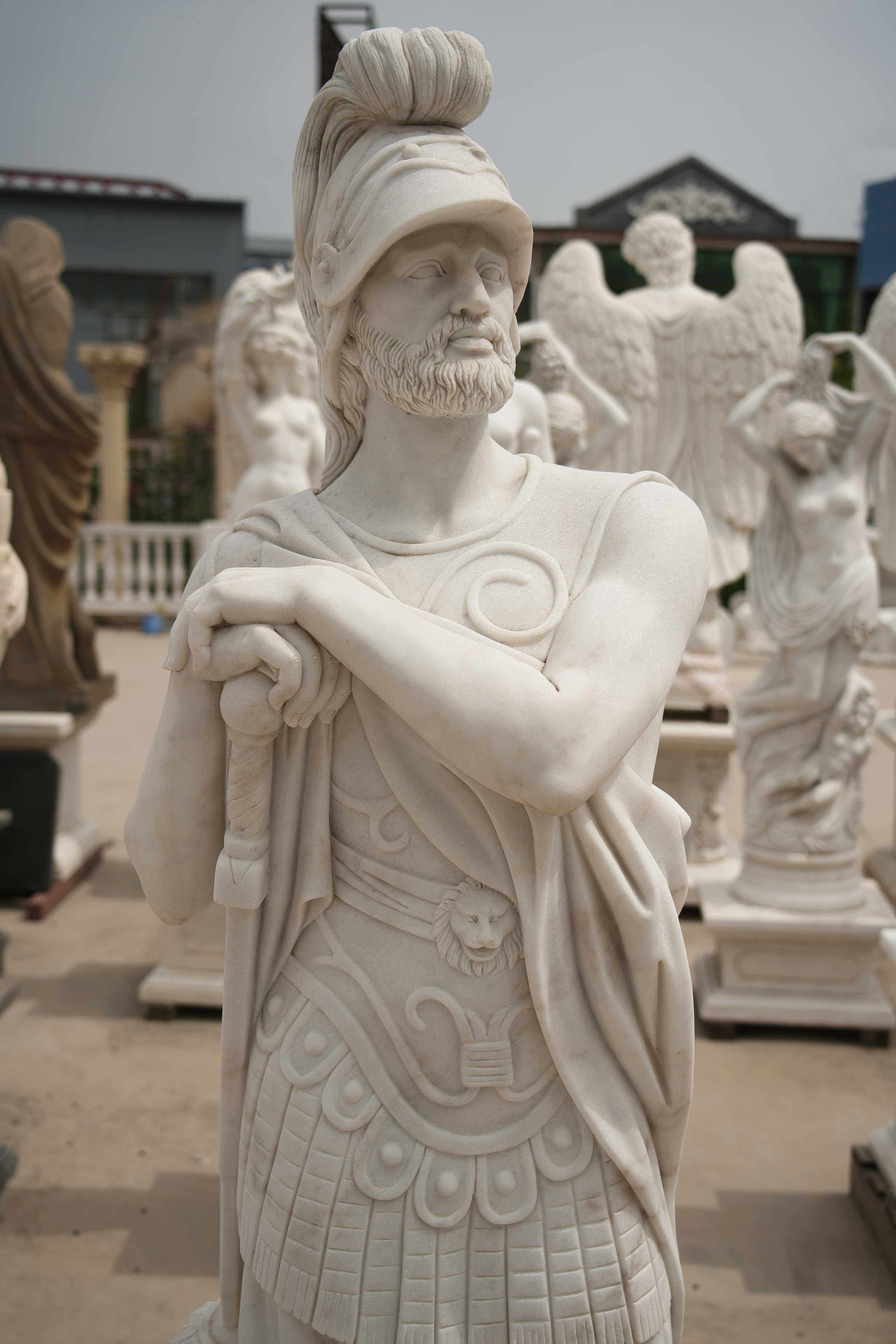Marble statue of a Roman warrior with detailed armor, standing confidently among other classical sculptures in an outdoor setting