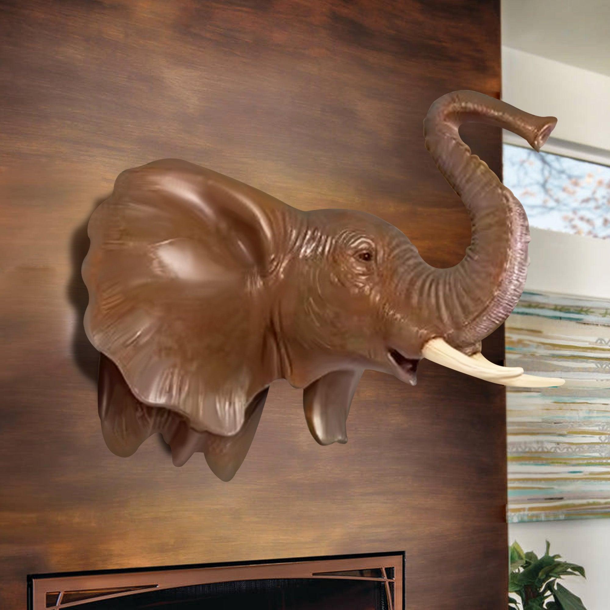 elephant head statue with two white ivories decorate on the wall above the fireplace