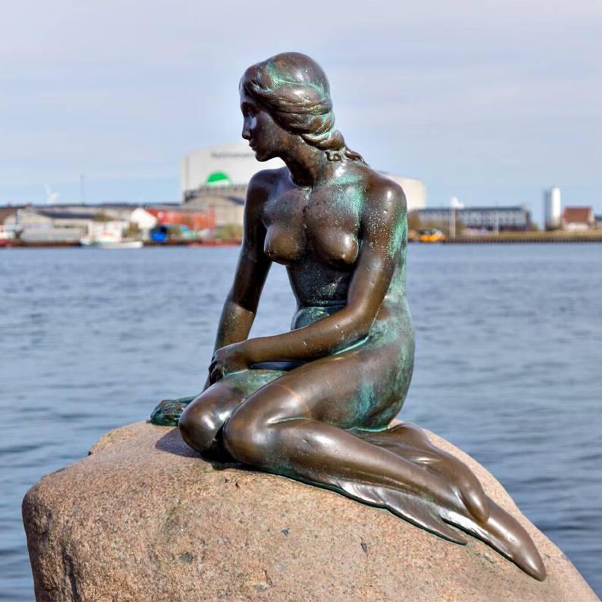 garden mermaid bronze statue lying beside the pond