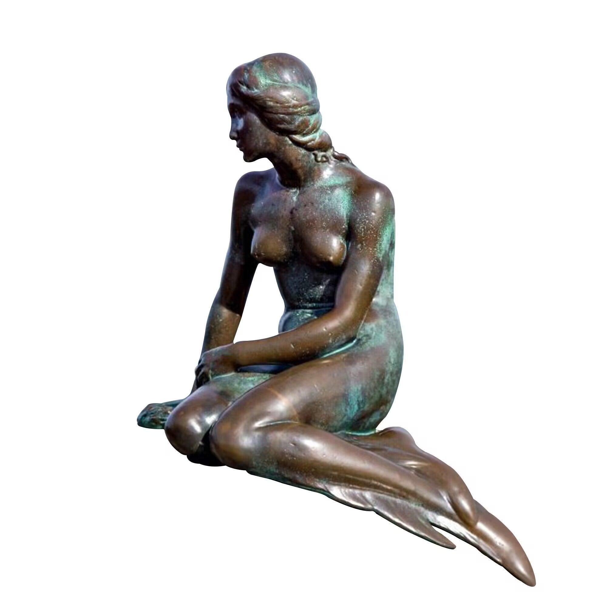 mermaid bronze statue lying beside the pond