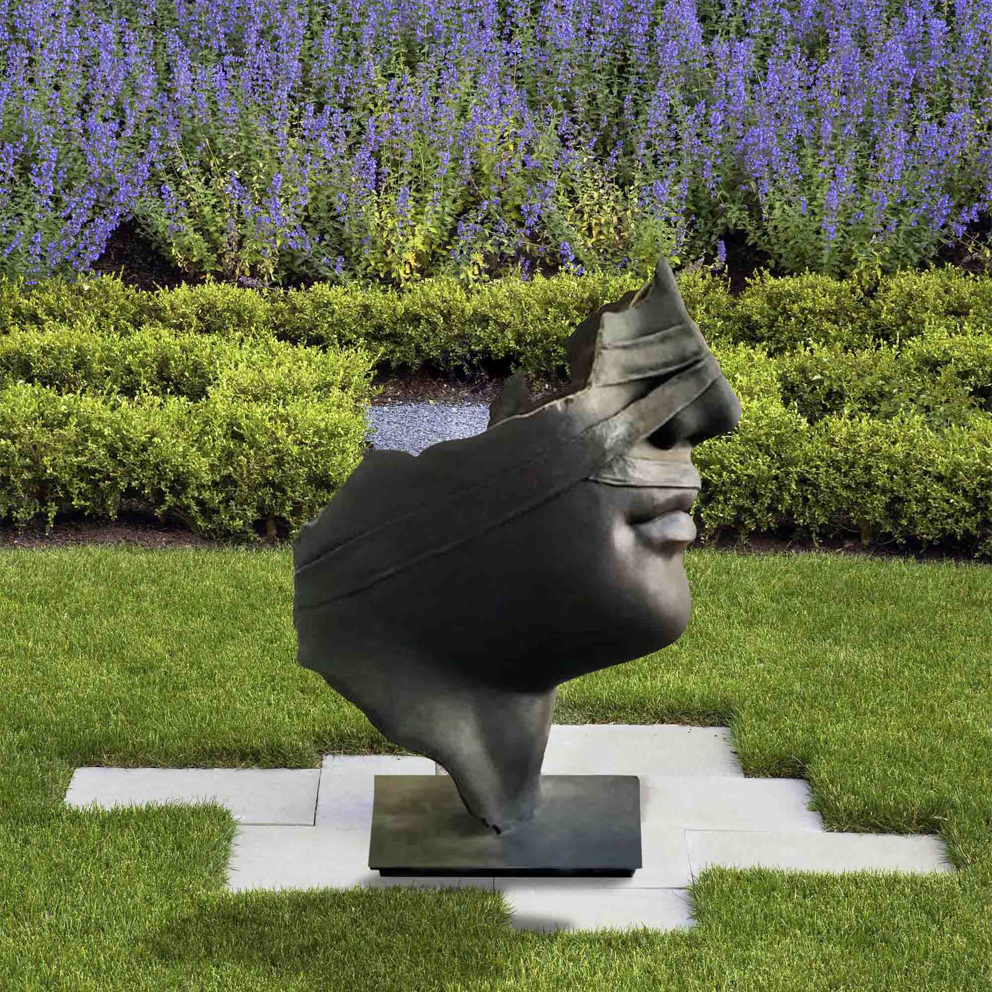 bronze broken face statue standing on lawn