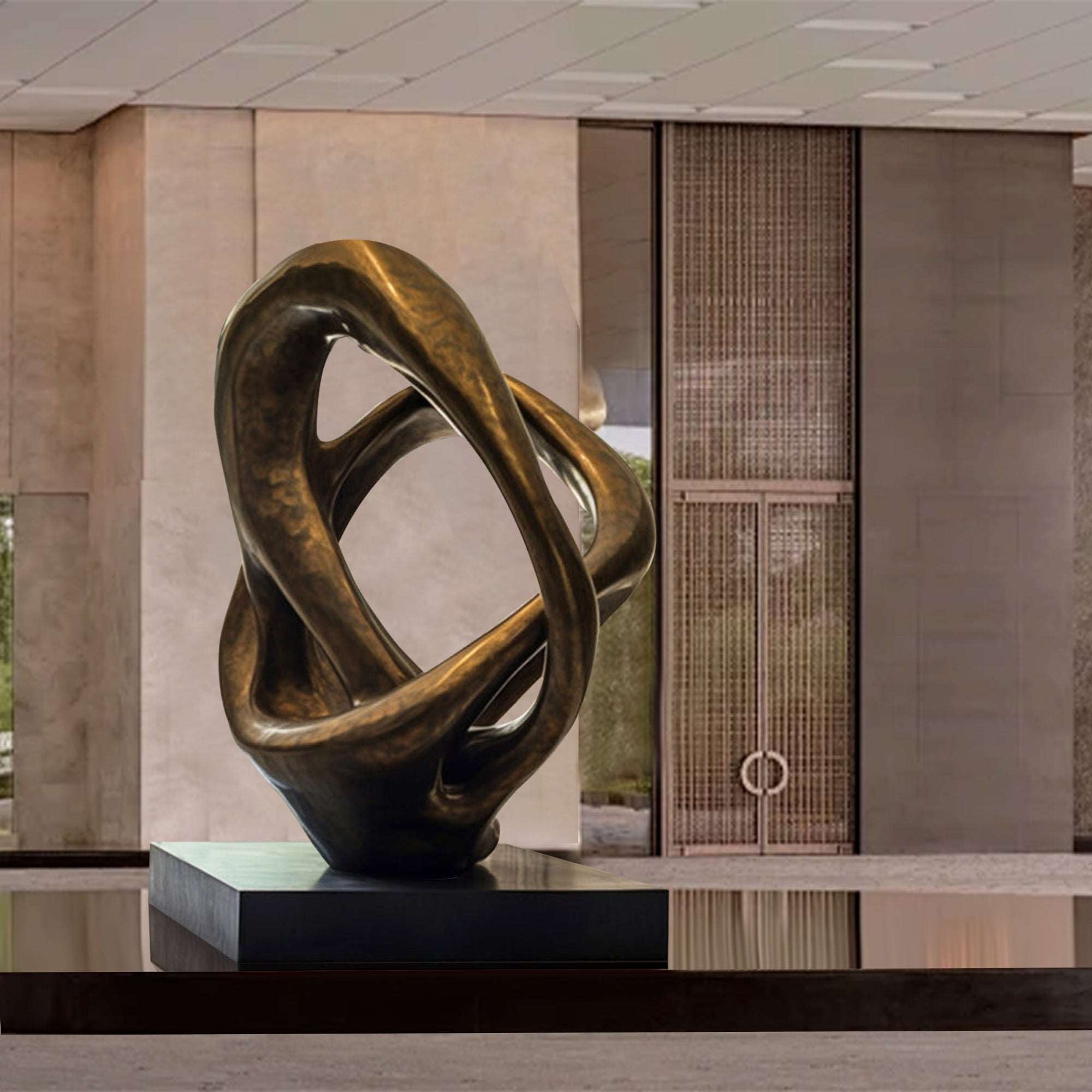 An abstract bronze sculpture with smooth, interwoven loops mounted on a black pedestal, displayed in a modern interior space with neutral tones and elegant surroundings