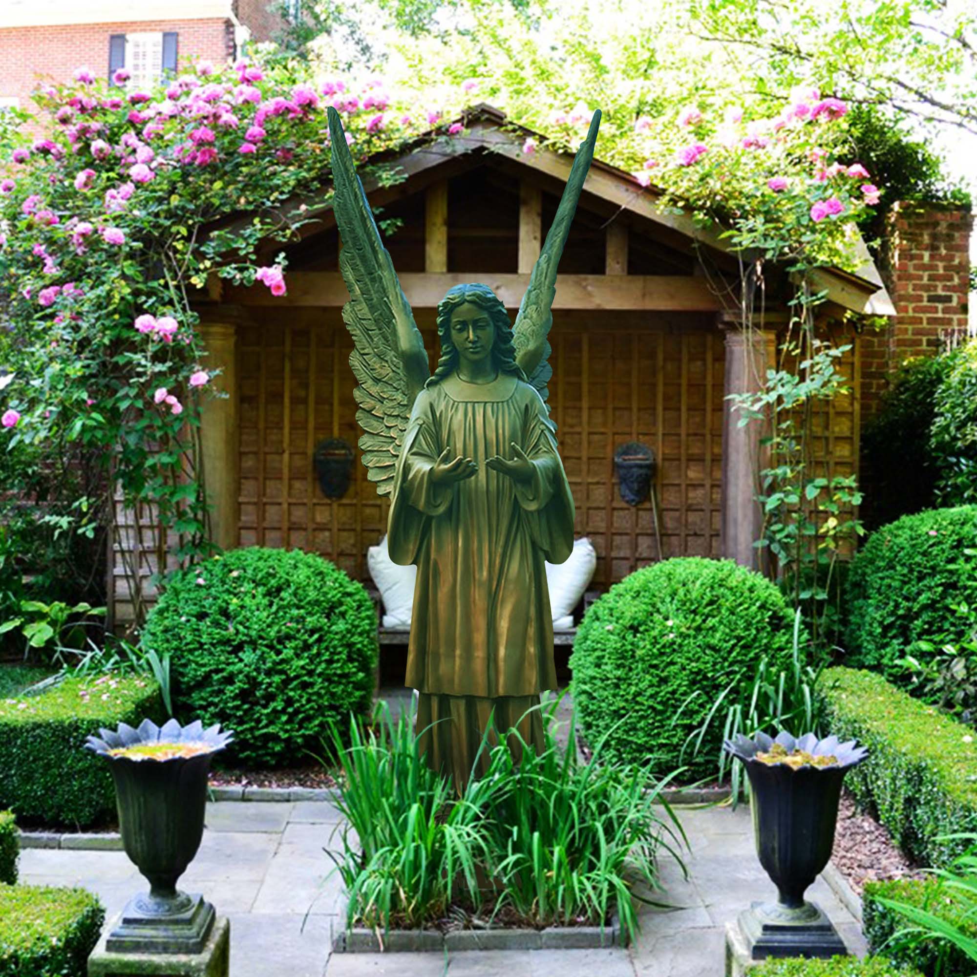 Bronze statue of a guardian angel with outstretched wings, placed in a serene garden setting.