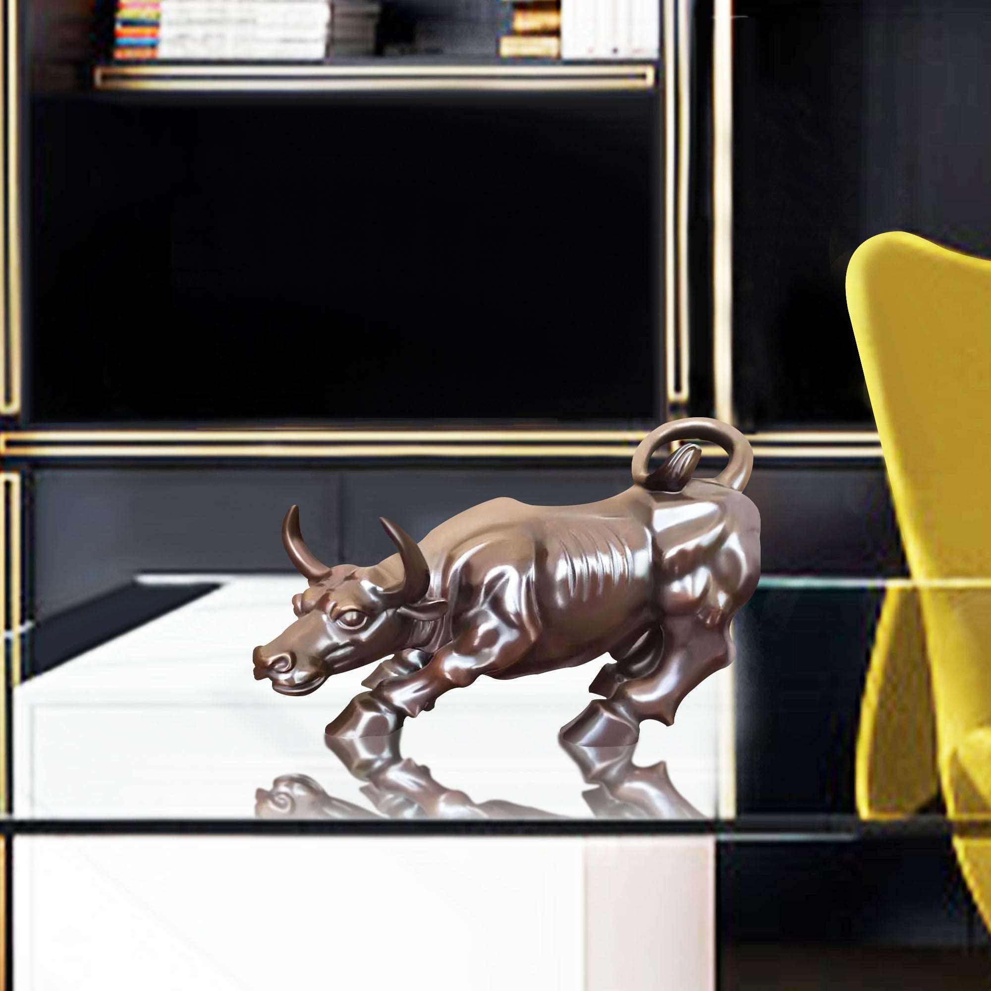 Bronze charging bull sculpture with a polished finish, displayed on a glass table in a modern office setting.