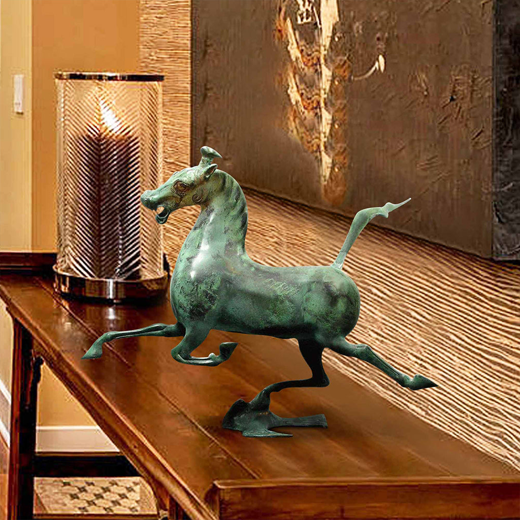 bronze sculpture replica of a Chinese galloping horse treading on a flying swallow, finished with an aged patina, displayed on a wooden console table