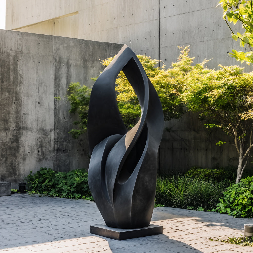 Abstract black sculpture in a garden setting with concrete wall and greenery