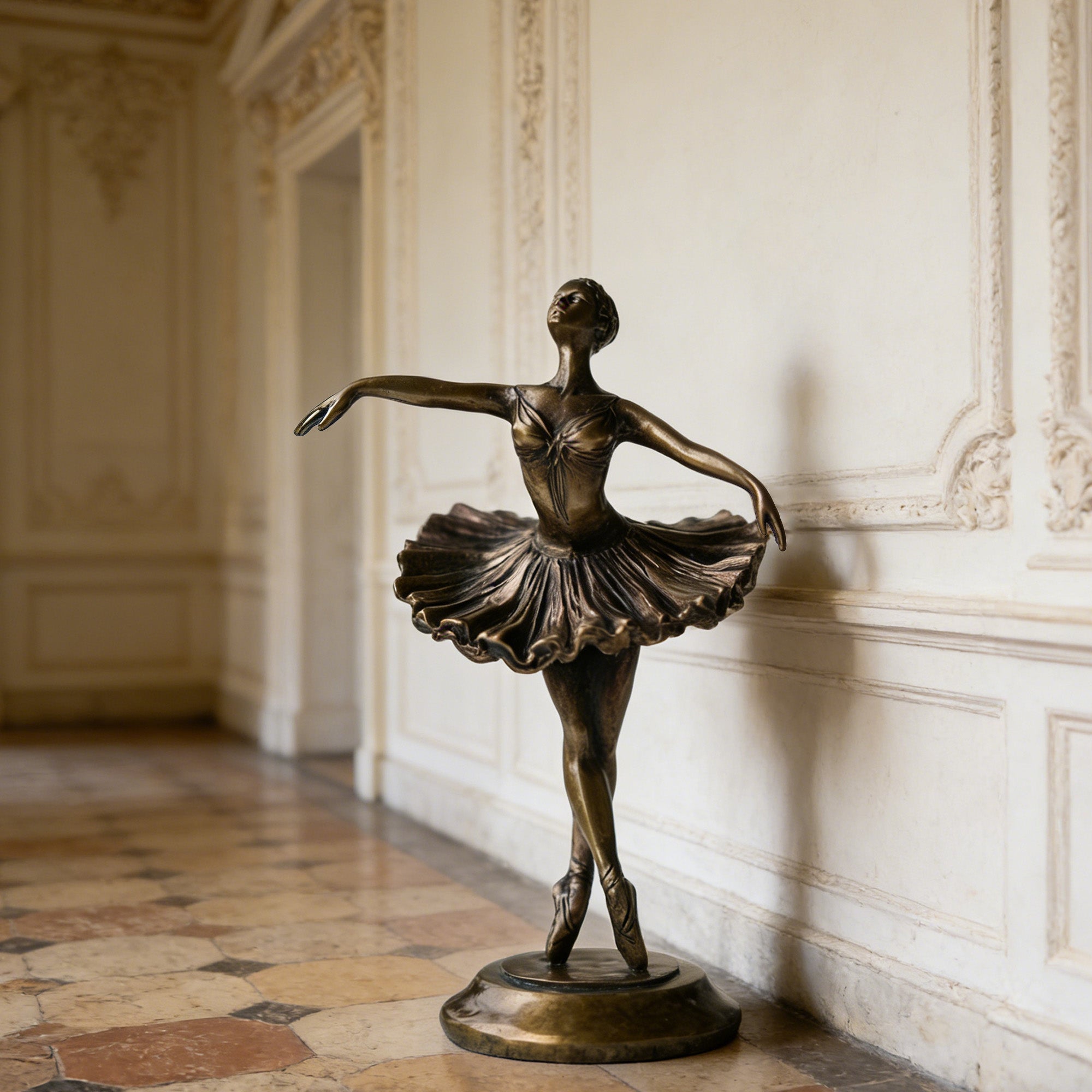 Bronze statue of a ballerina in a classical pose against an ornate wall.