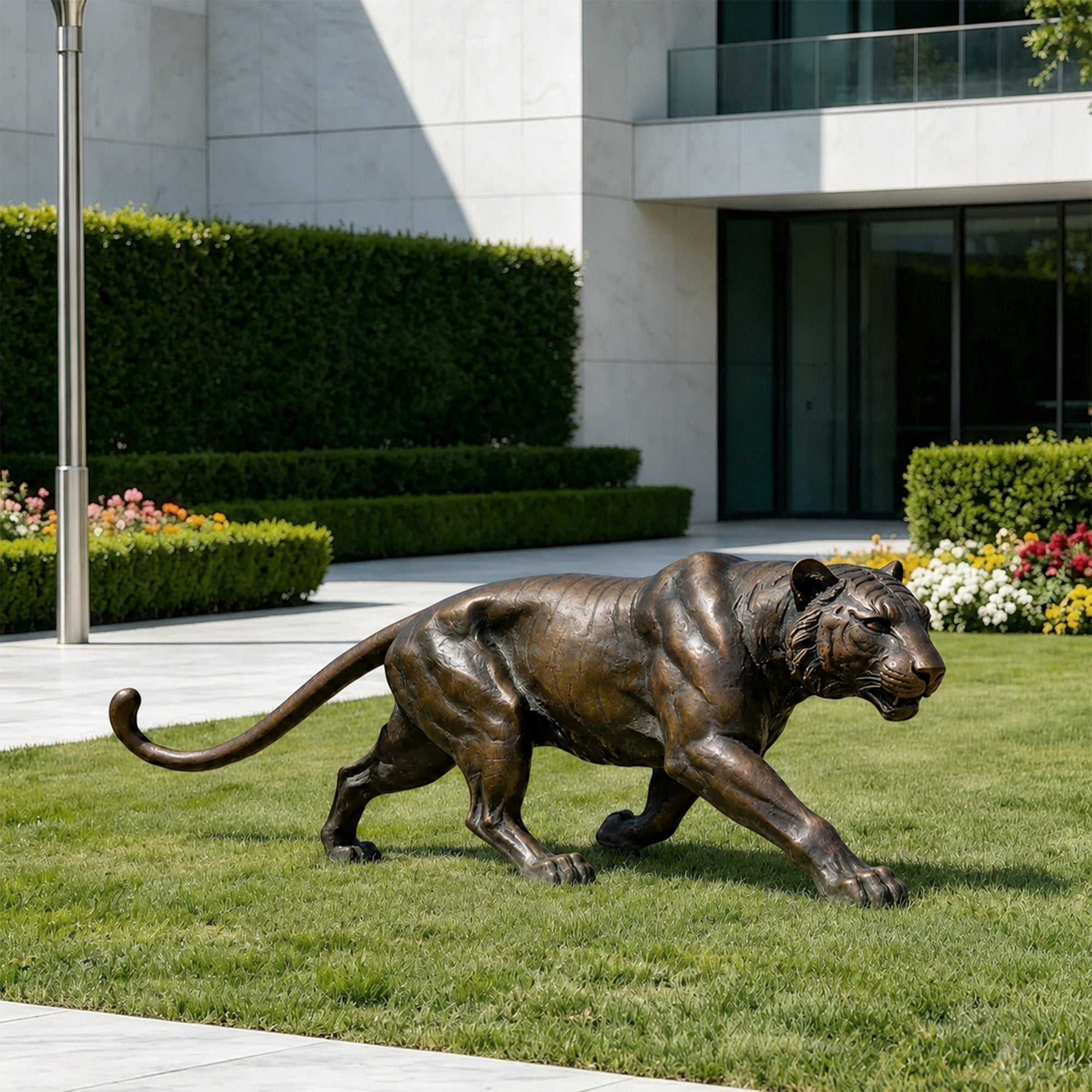 Realistic bronze tiger statue displayed on a lawn outside a modern building