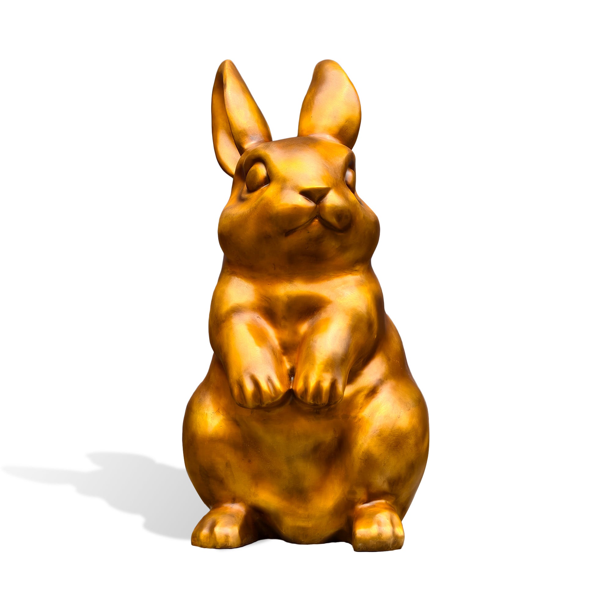 Front view of a golden bronze rabbit statue with upright ears, rounded cheeks, lifted front paws, and a full seated body on a white background.