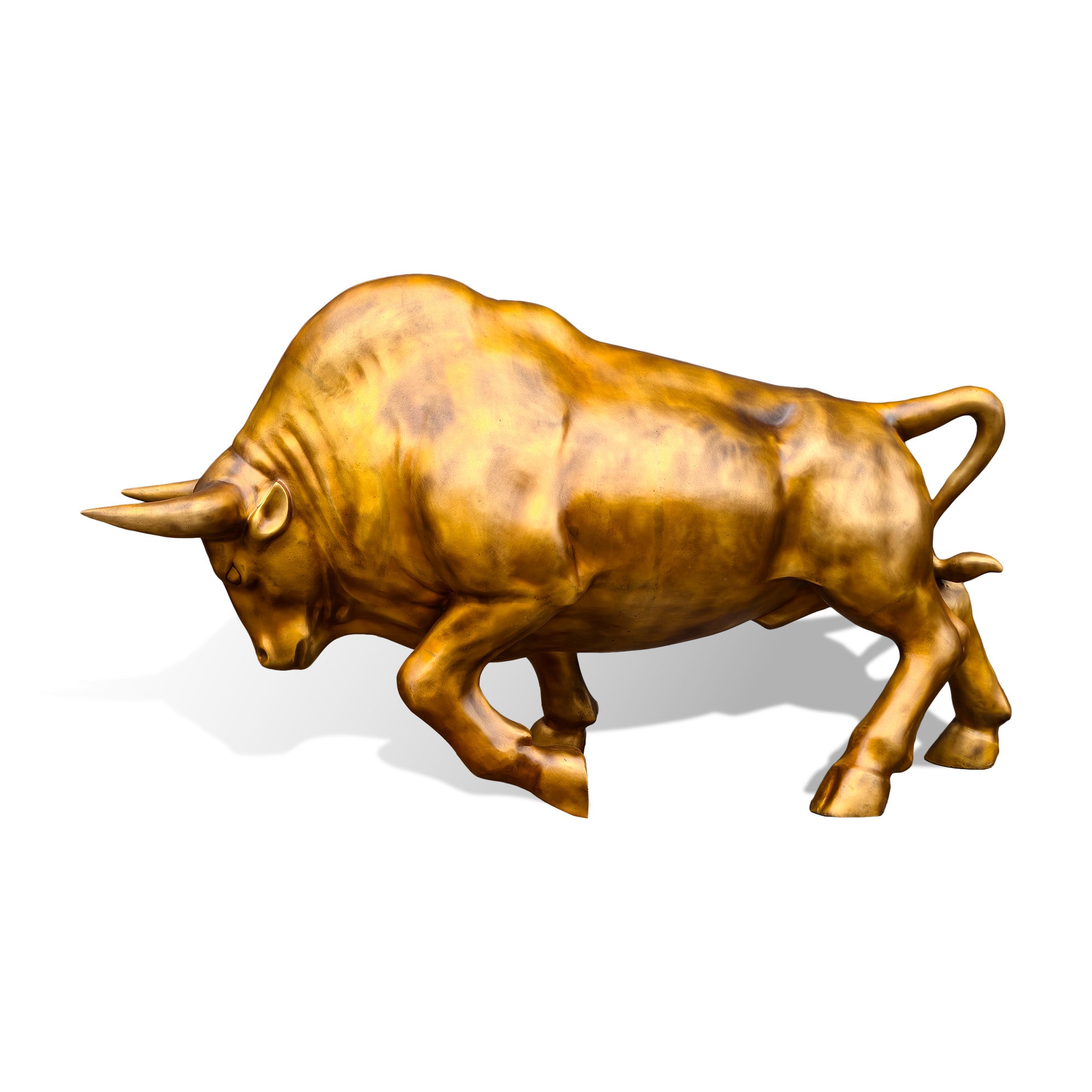 Left-facing side of a golden bronze charging bull sculpture with a lowered head, prominent horns, powerful shoulders, lifted front hoof, and dynamic forward movement
