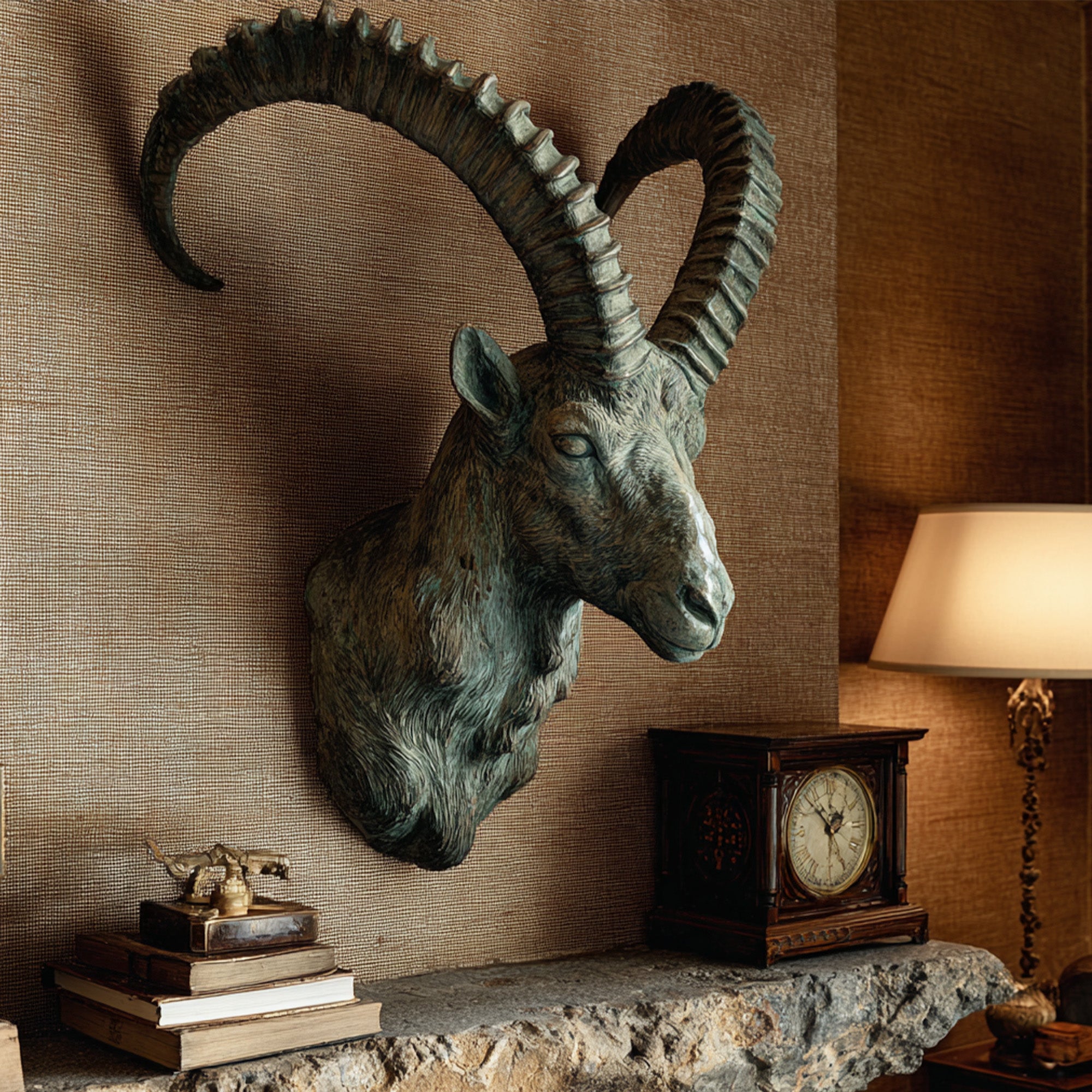 Bronze ram head wall sculpture displayed on an interior textured wall with large curved horns, detailed fur texture, antique patina, and rustic decorative surroundings.
