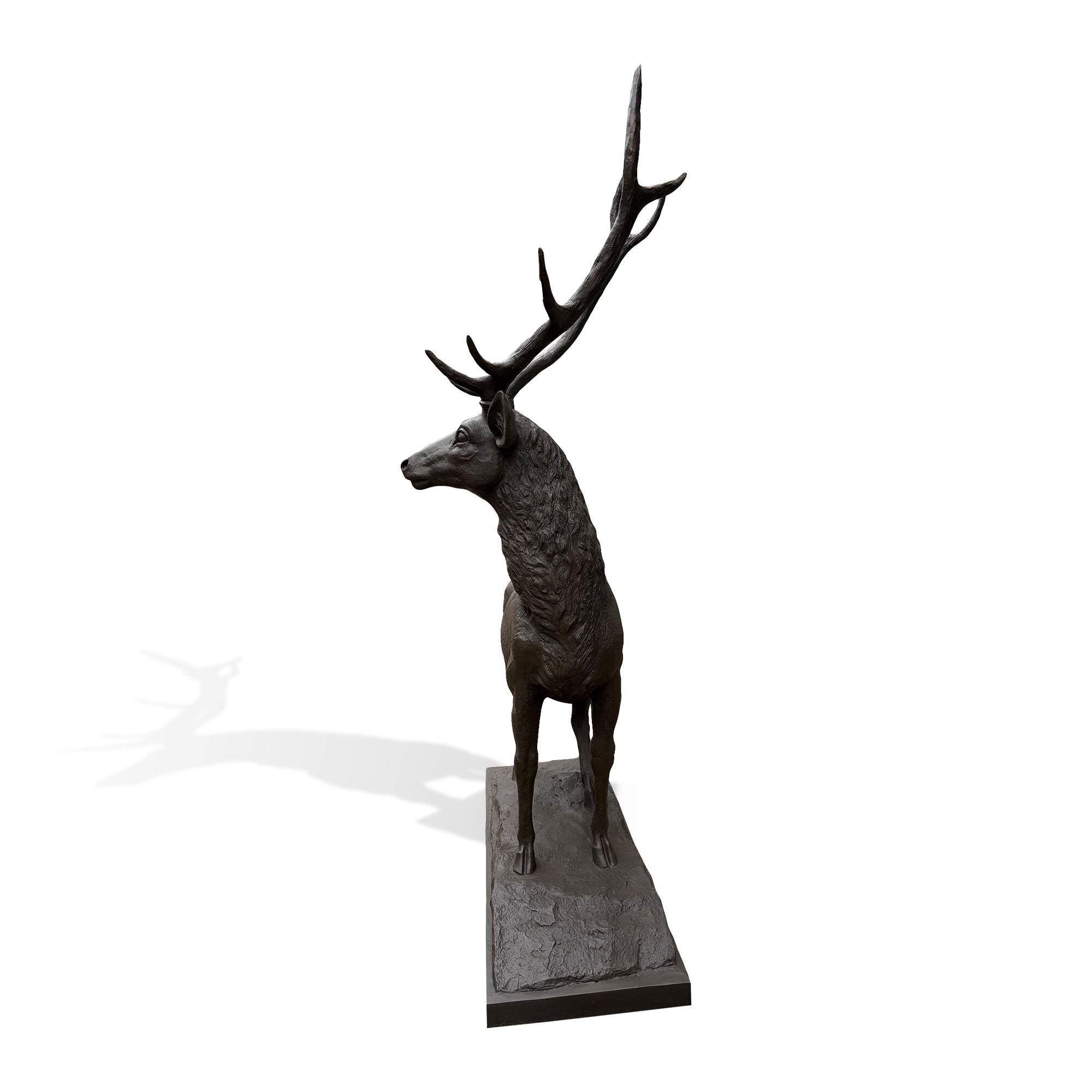 Bronze deer statue showing tall antlers, alert head posture, detailed neck texture, and sculpted outdoor landscape base