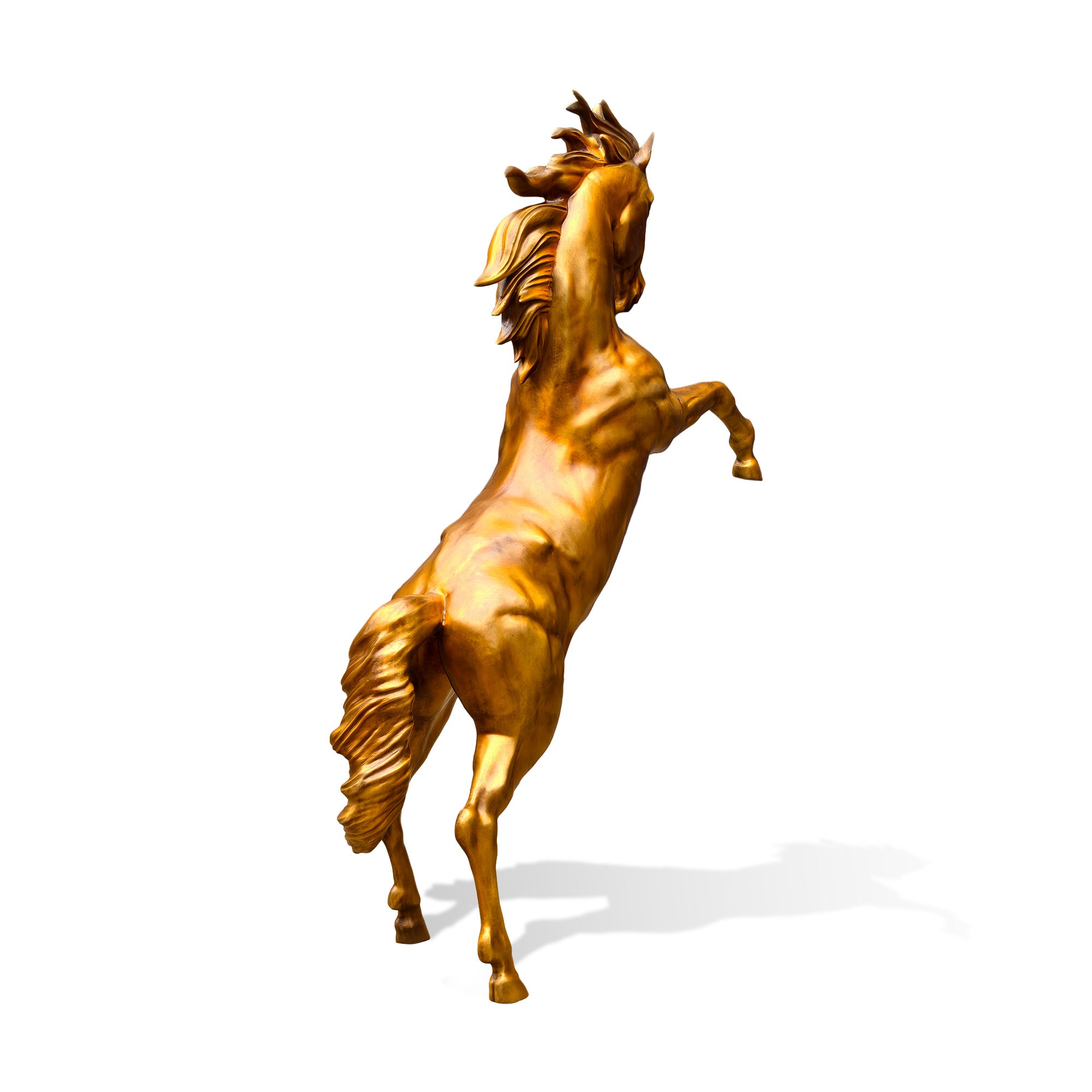 Rear three-quarter view of a golden bronze rearing horse statue with flowing mane, lifted front legs, sculpted back muscles, raised tail, and powerful vertical movement on a white background.