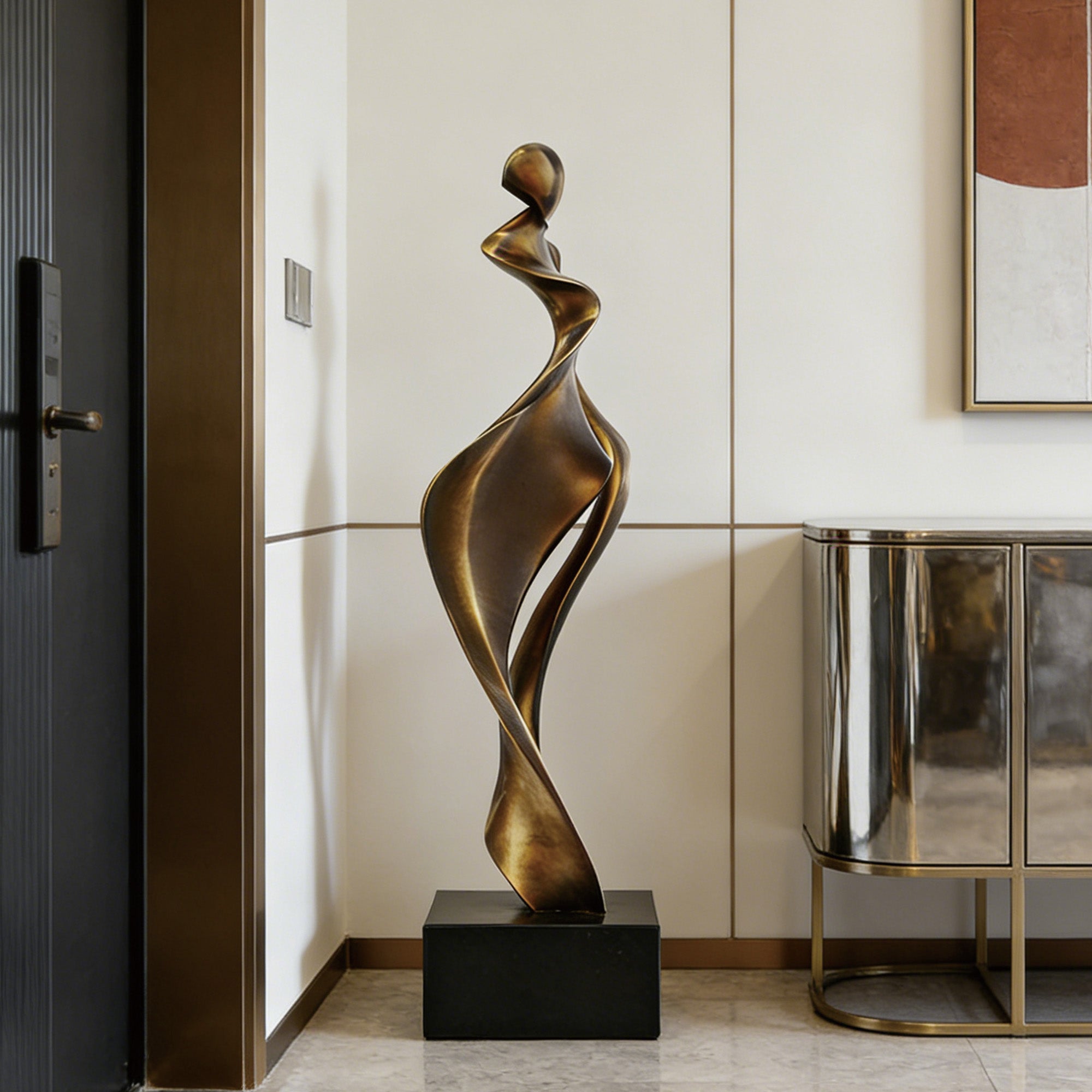 Bronze abstract figure sculpture displayed in a modern entryway with flowing ribbon-like curves, elongated vertical form, dark square base, and elegant interior setting.