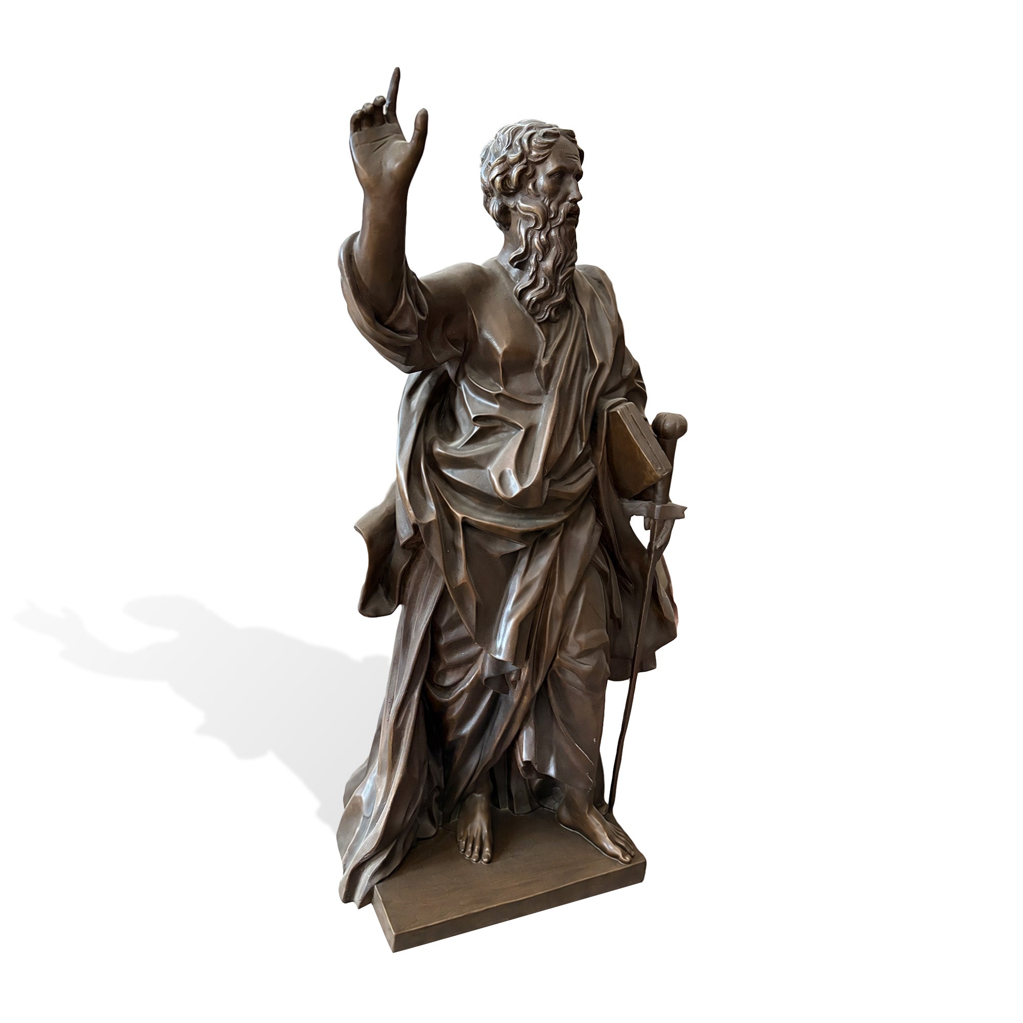Right three-quarter view of a bronze Saint Paul Apostle sculpture holding a book and sword, with raised hand, classical robe folds, long beard, and religious Christian detail.