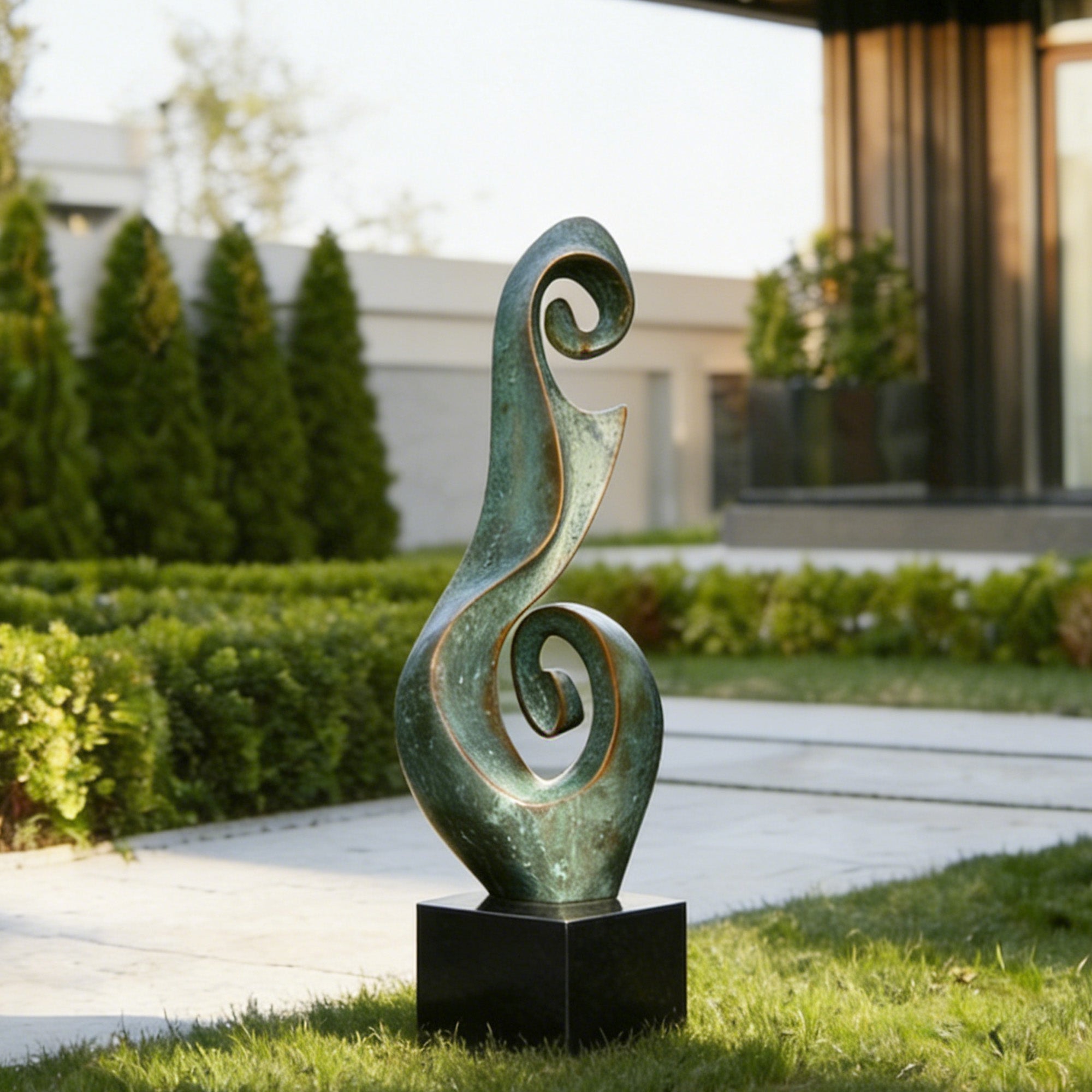 Verdigris bronze spiral sculpture displayed on a black pedestal in a modern garden courtyard with curling scroll forms, open negative space, and aged green patina.