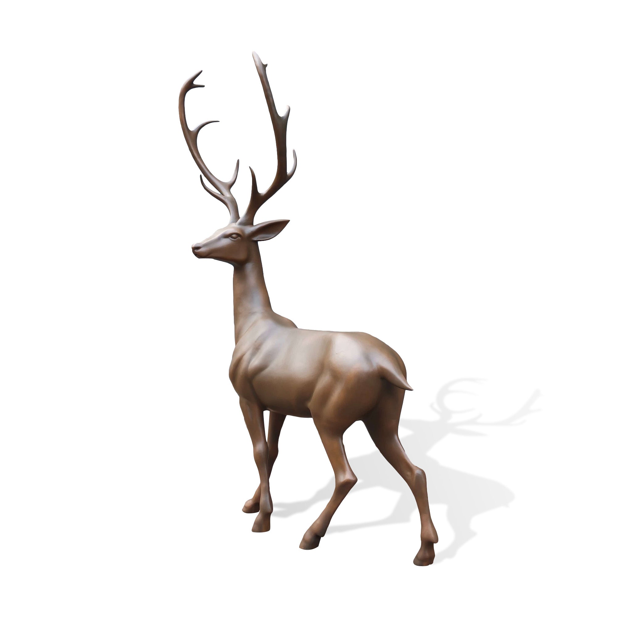 Life-size bronze deer sculpture viewed from a three-quarter angle, highlighting the noble stag profile, sweeping antlers, muscular form, and graceful walking stance.