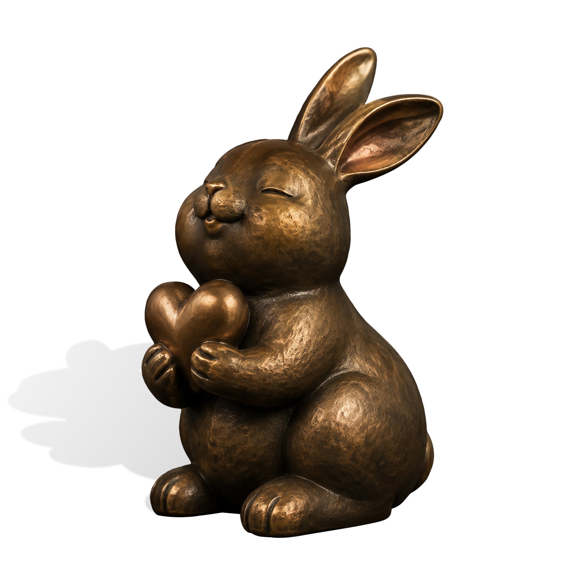 Front three-quarter product view of a seated bronze bunny sculpture with long upright ears, closed eyes, rounded features, and a heart held gently in both paws.