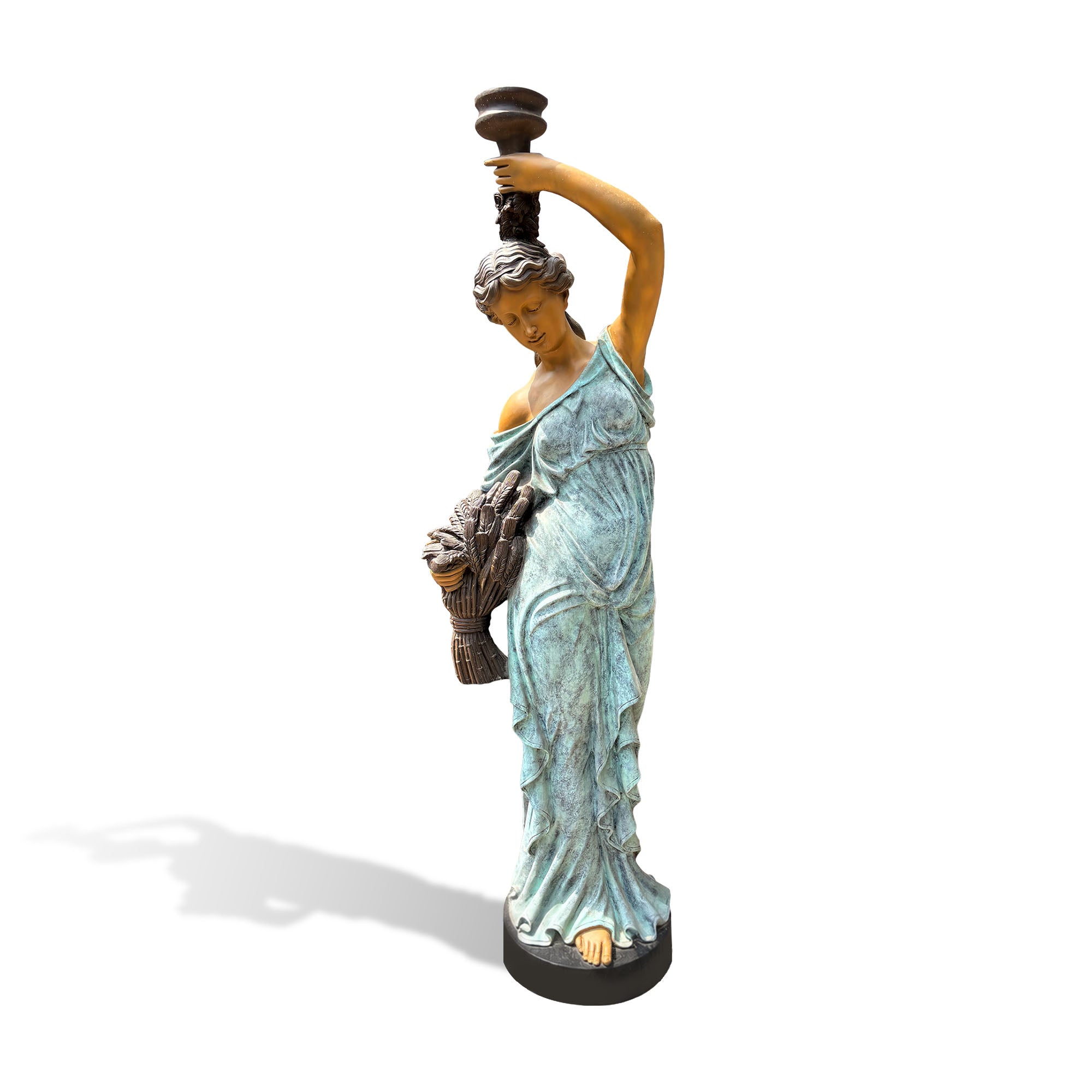 Front view of a bronze harvest woman sculpture featuring a verdigris patina finish, golden bronze skin, flowing drapery, raised vessel, and bundled grain.