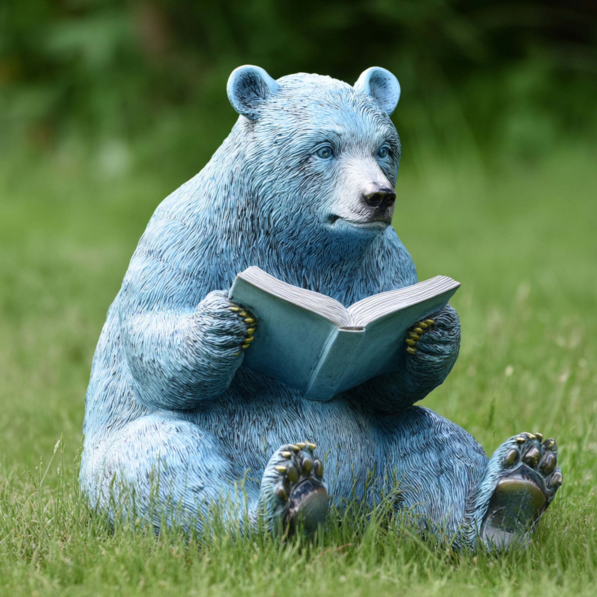 Reading bear garden sculpture sitting on grass holding an open book, decorative animal outdoor sculpture for landscape design
