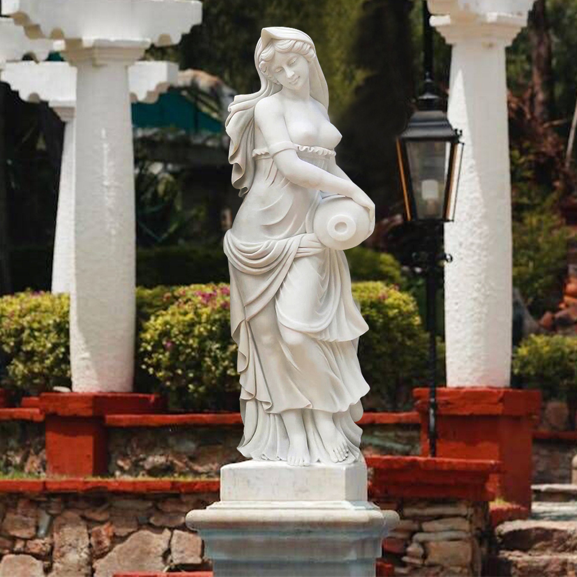 Marble statue of a Greek water maiden holding an amphora, with flowing robes, displayed in a garden setting.