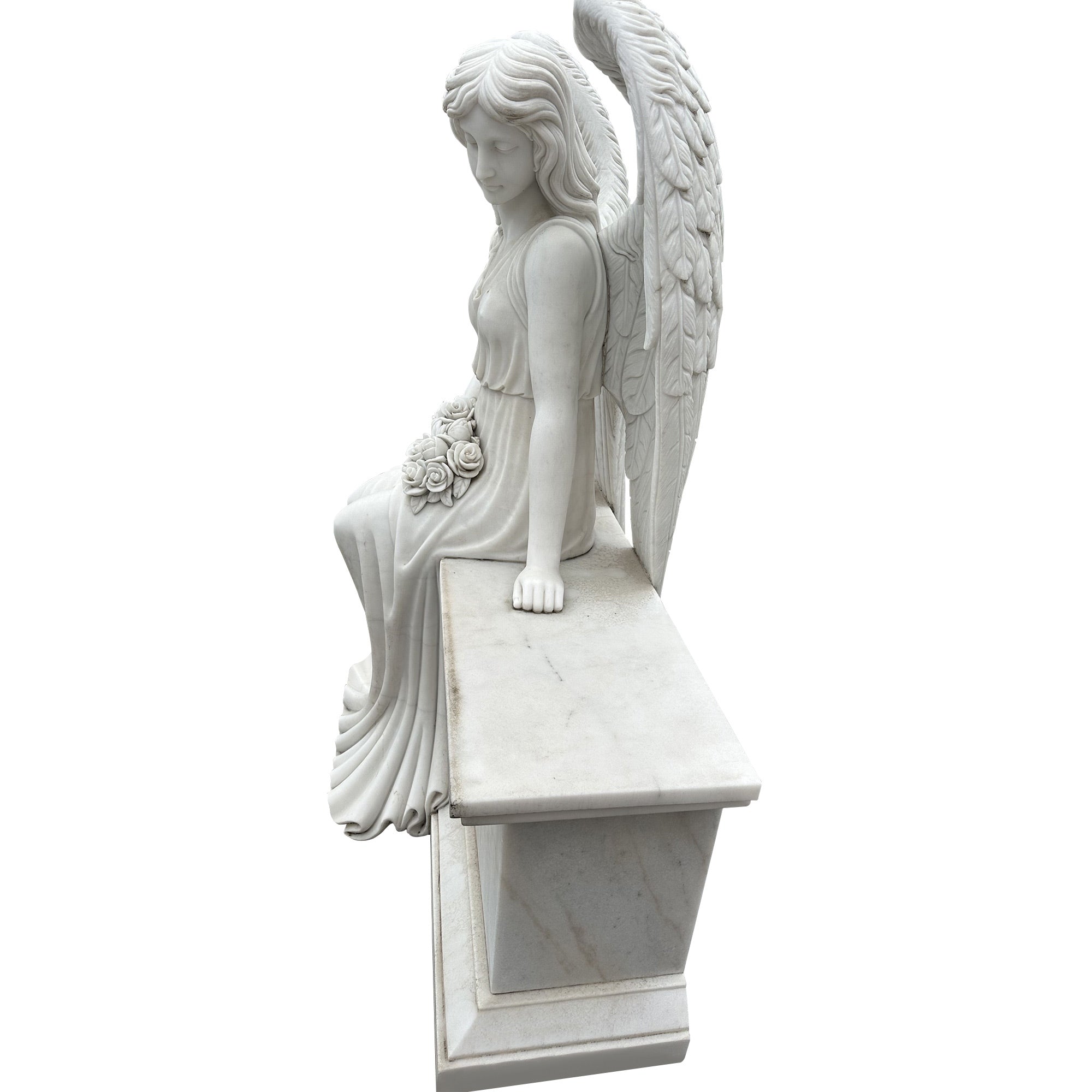 Stone angel statue seated on a bench holding roses side view