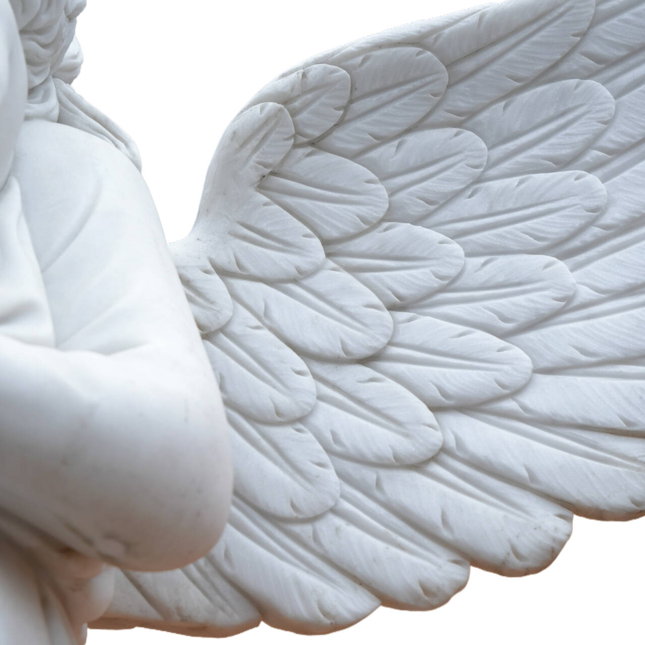 Close-up of a white marble angel sculpture wing, showing hand-carved feather details and fine craftsmanship in the stone.